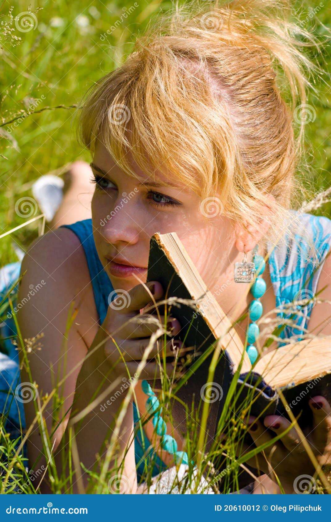 Blonde girl in grass with book