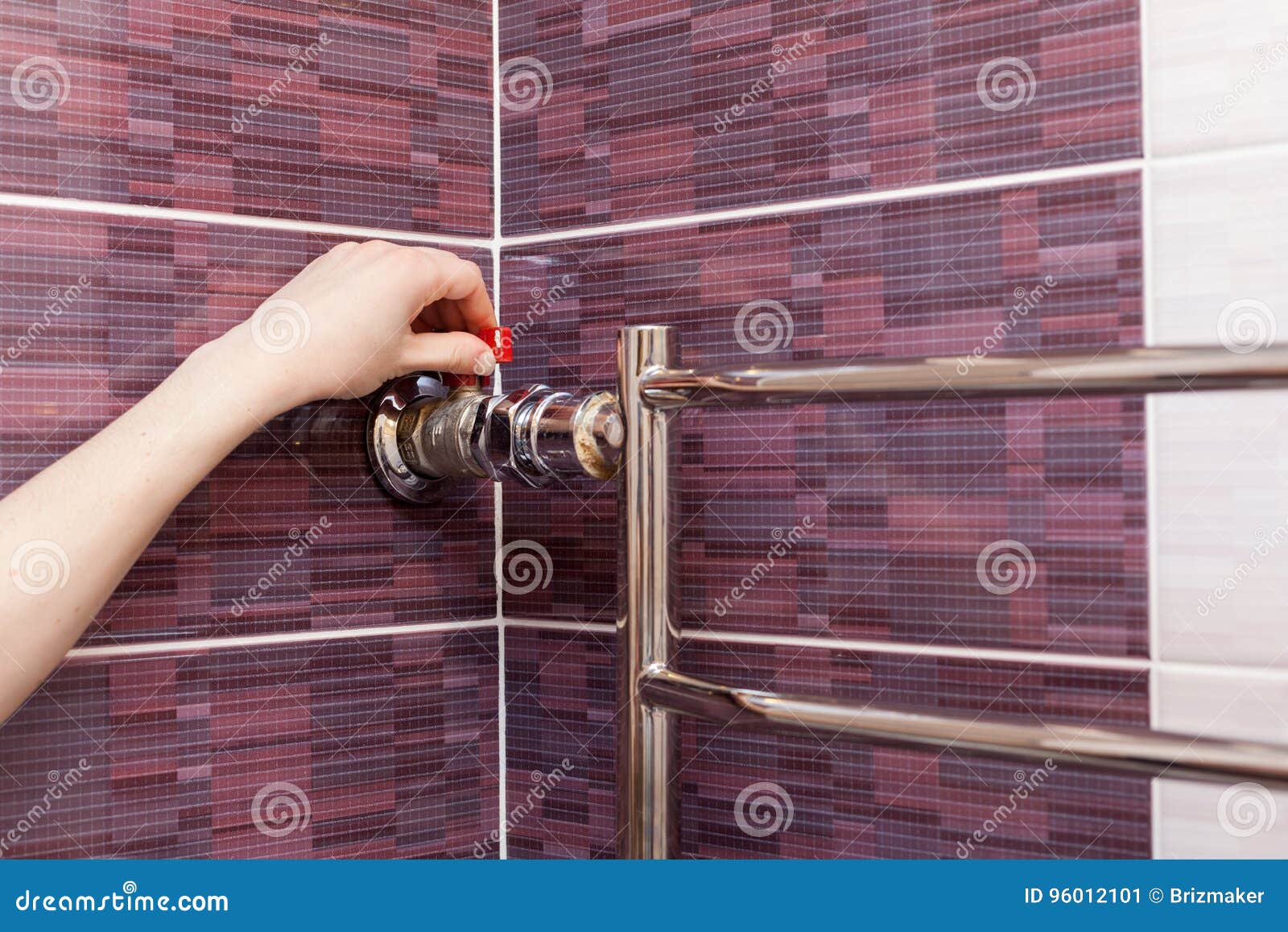 the girl hand regulates the water tap in the heated towel rail.