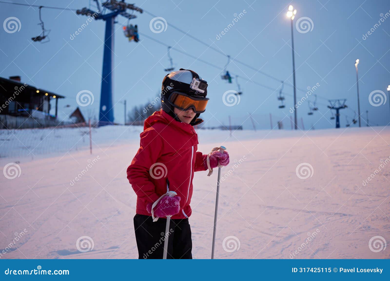 girl in helmet with camera skiing on snowy slope