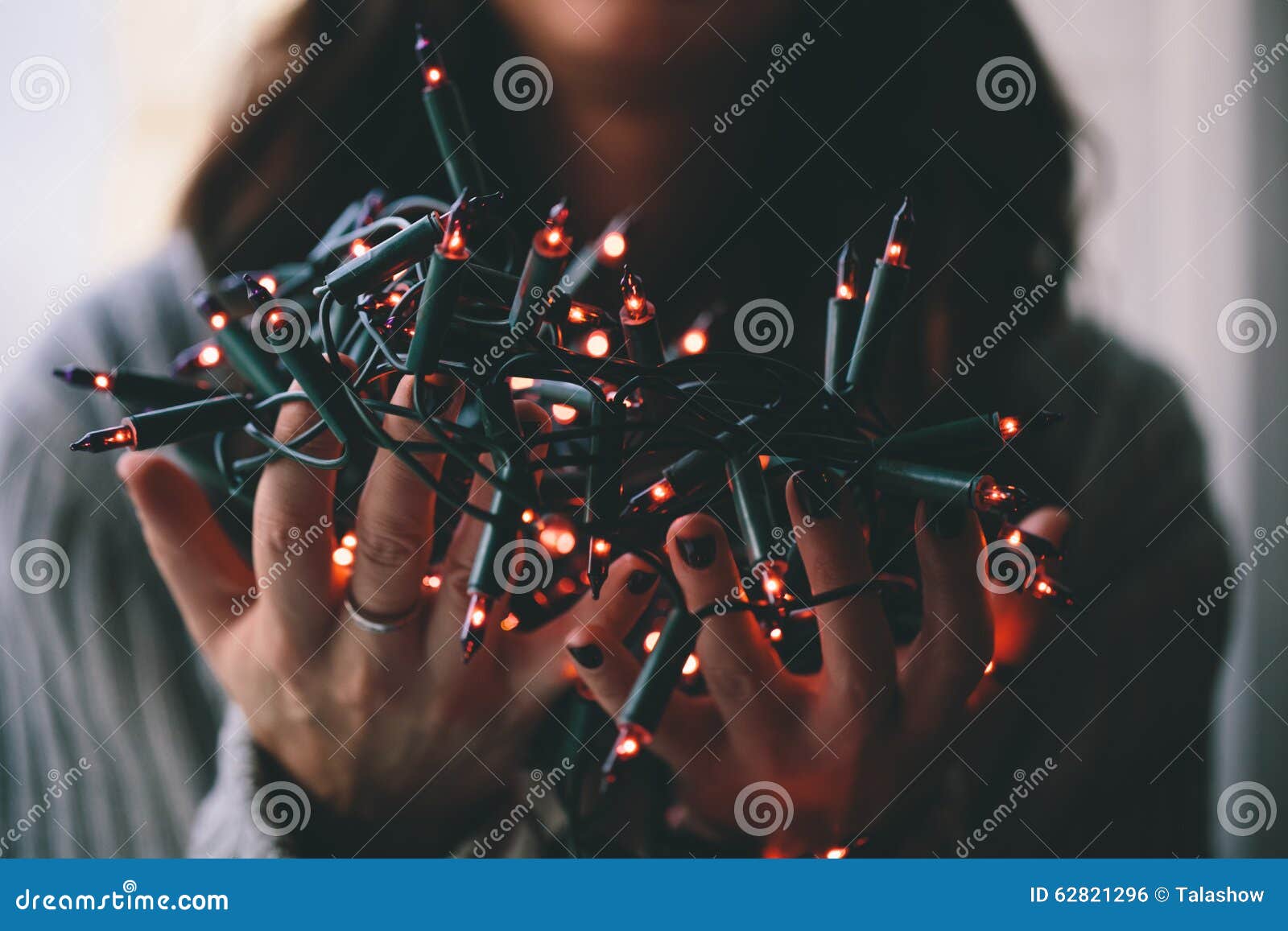 Girl holding a Christmas lamp garland closeup photo.