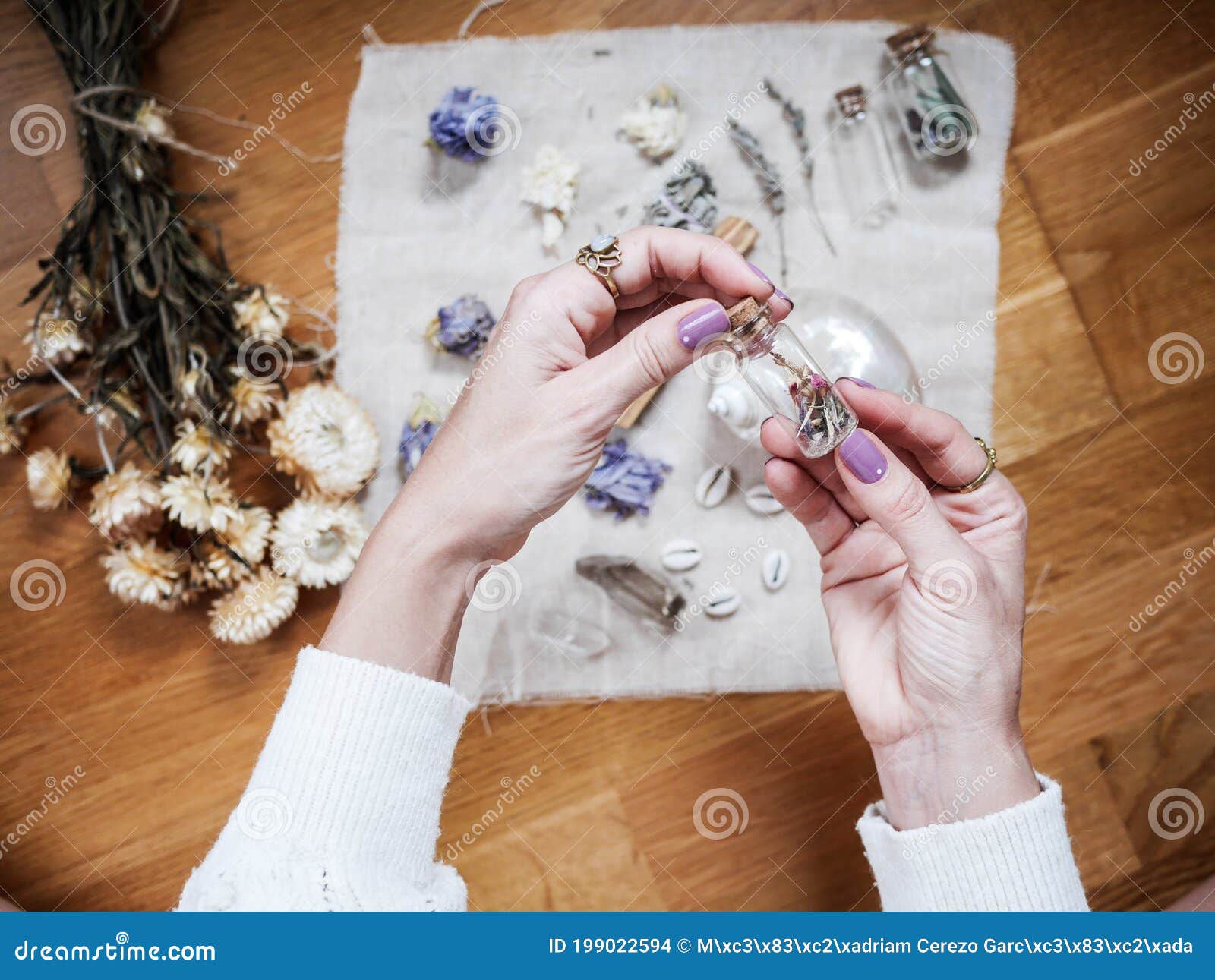 a girl is holding a little glass jar  on her altar in lavender tones