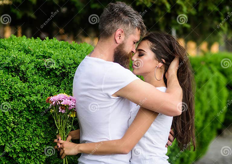 Girl Holds Flowers While Man Caress Her Long Hair Couple In Love Hugs Outdoors Park Background