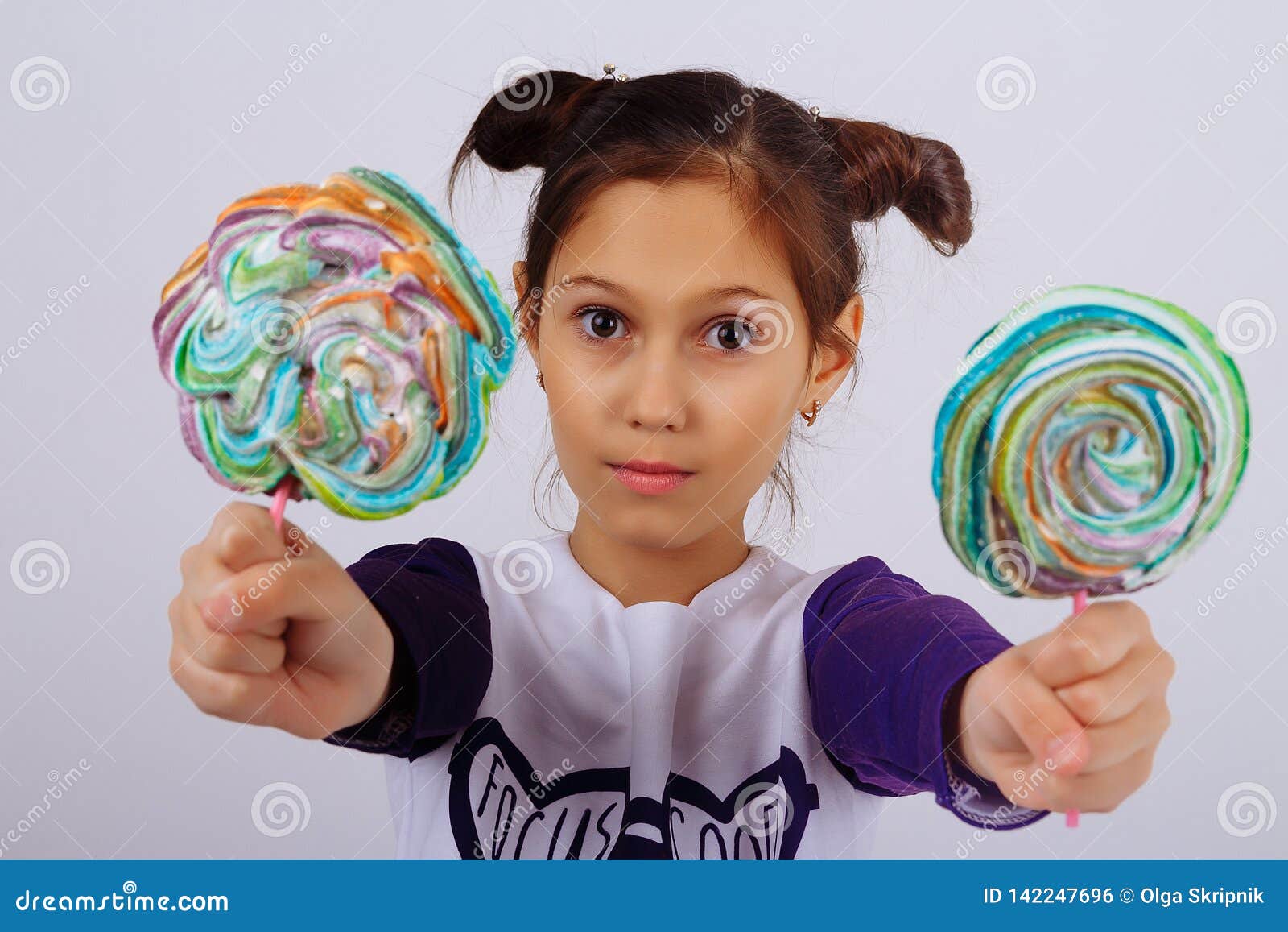 A Girl Holds In Two Hands Multicolored Candies On A Stick Showing Them