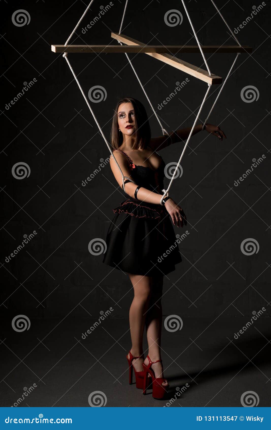 Girl in the Image of Marionette Against Black Wall Stock Image