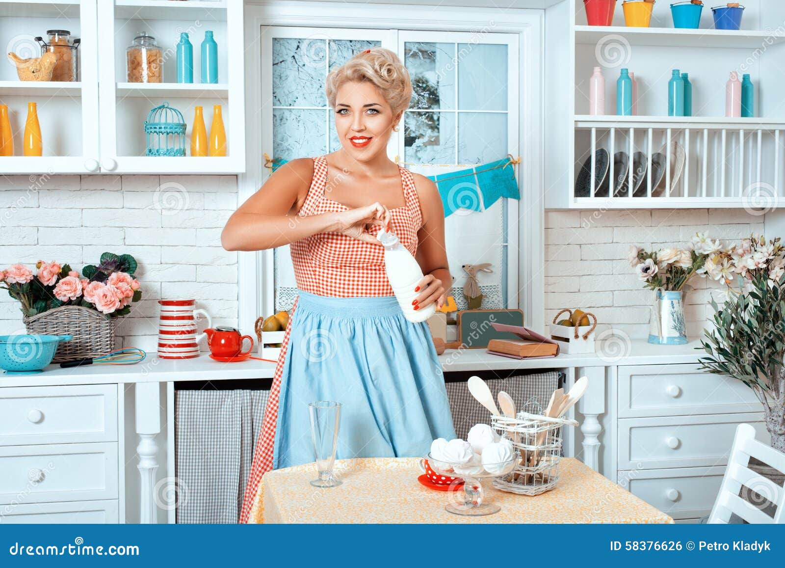 Girl is in the Kitchen and Holding Bottle of Milk. Stock Photo Image