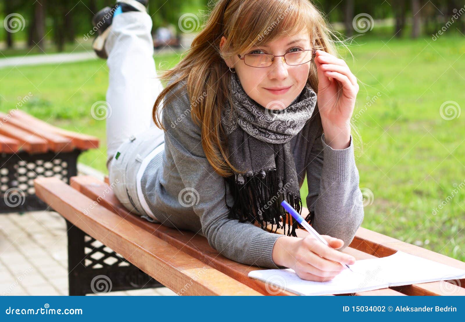 the girl lays on a bench, and writes