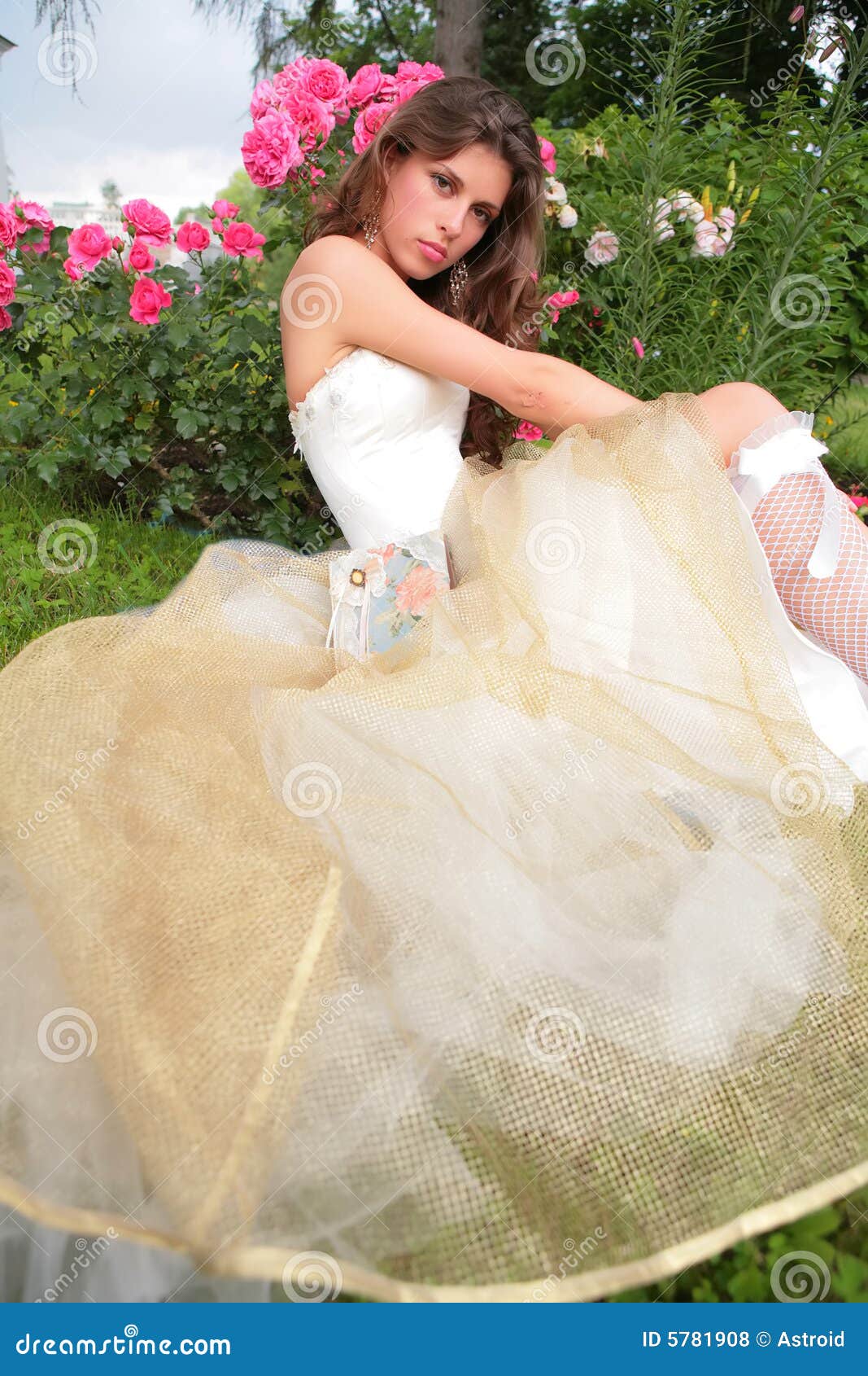 girl in luxurious gown near rosebush