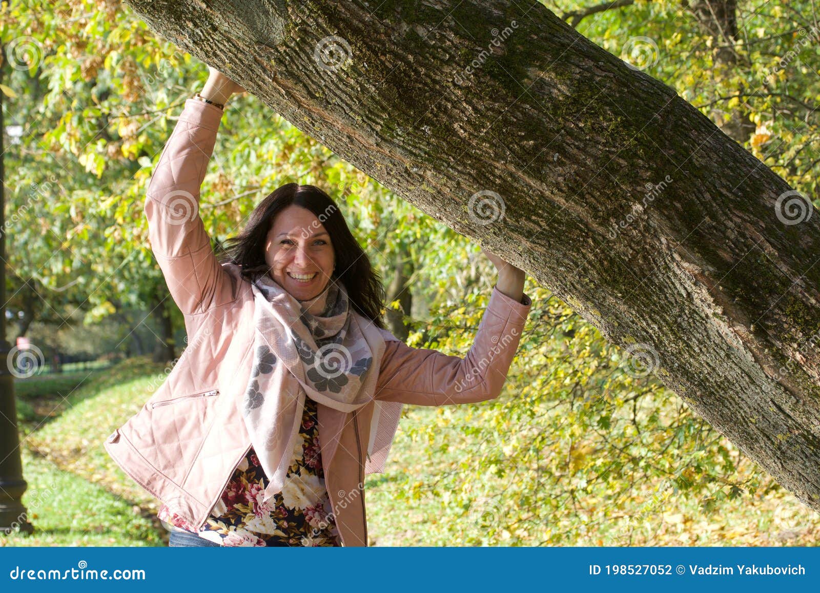 Girl Near a Leaning Tree in an Autumn Park. she Put Her Hands on the ...