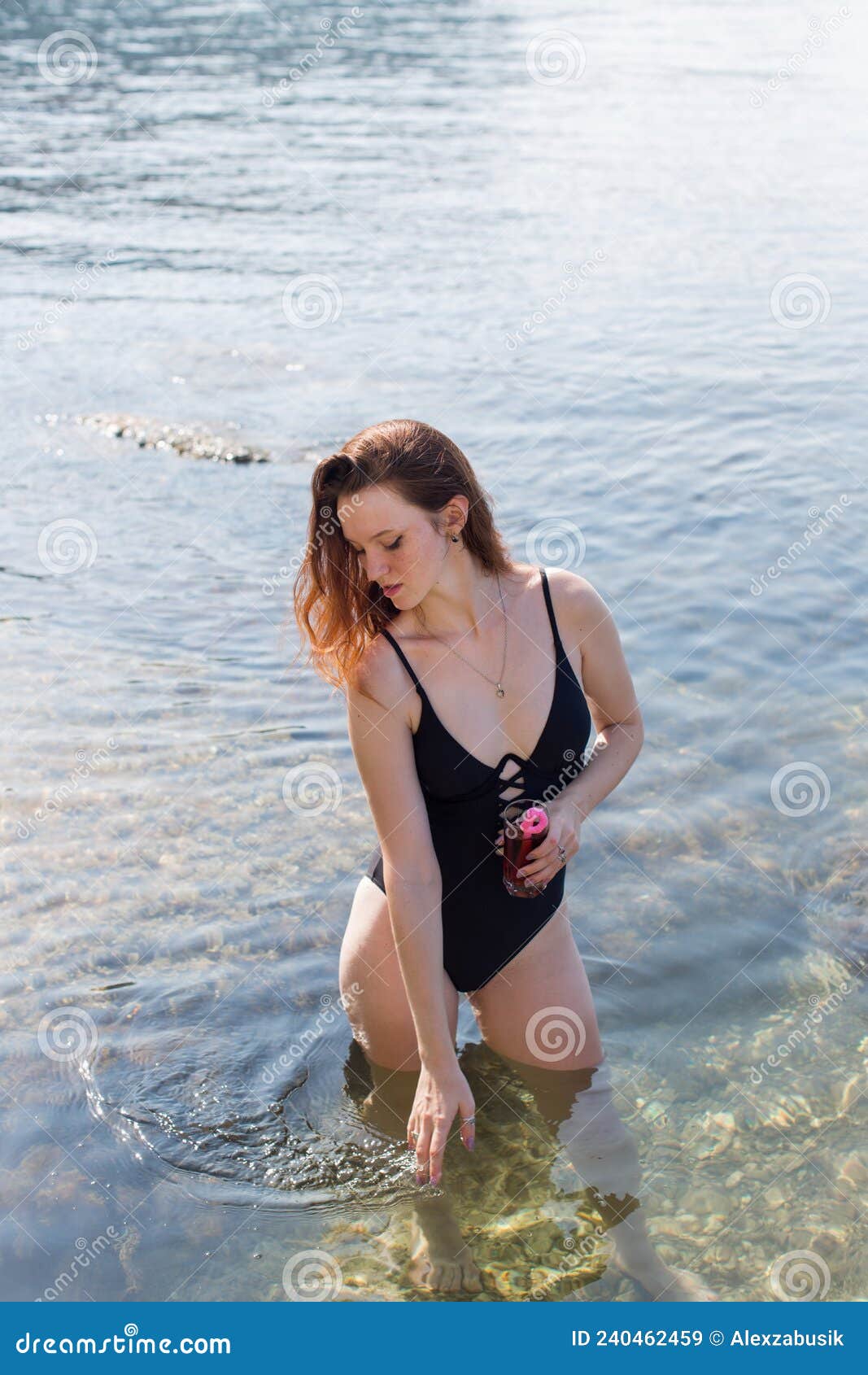 Happy wet girl in one-piece swimwear posing against sea Stock