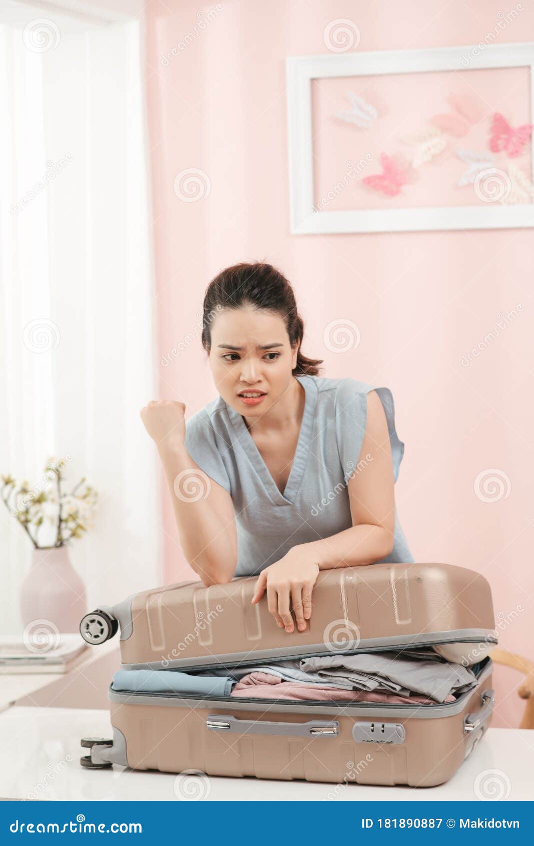 girl packing for travel, closing hardly overflowing luggage bag