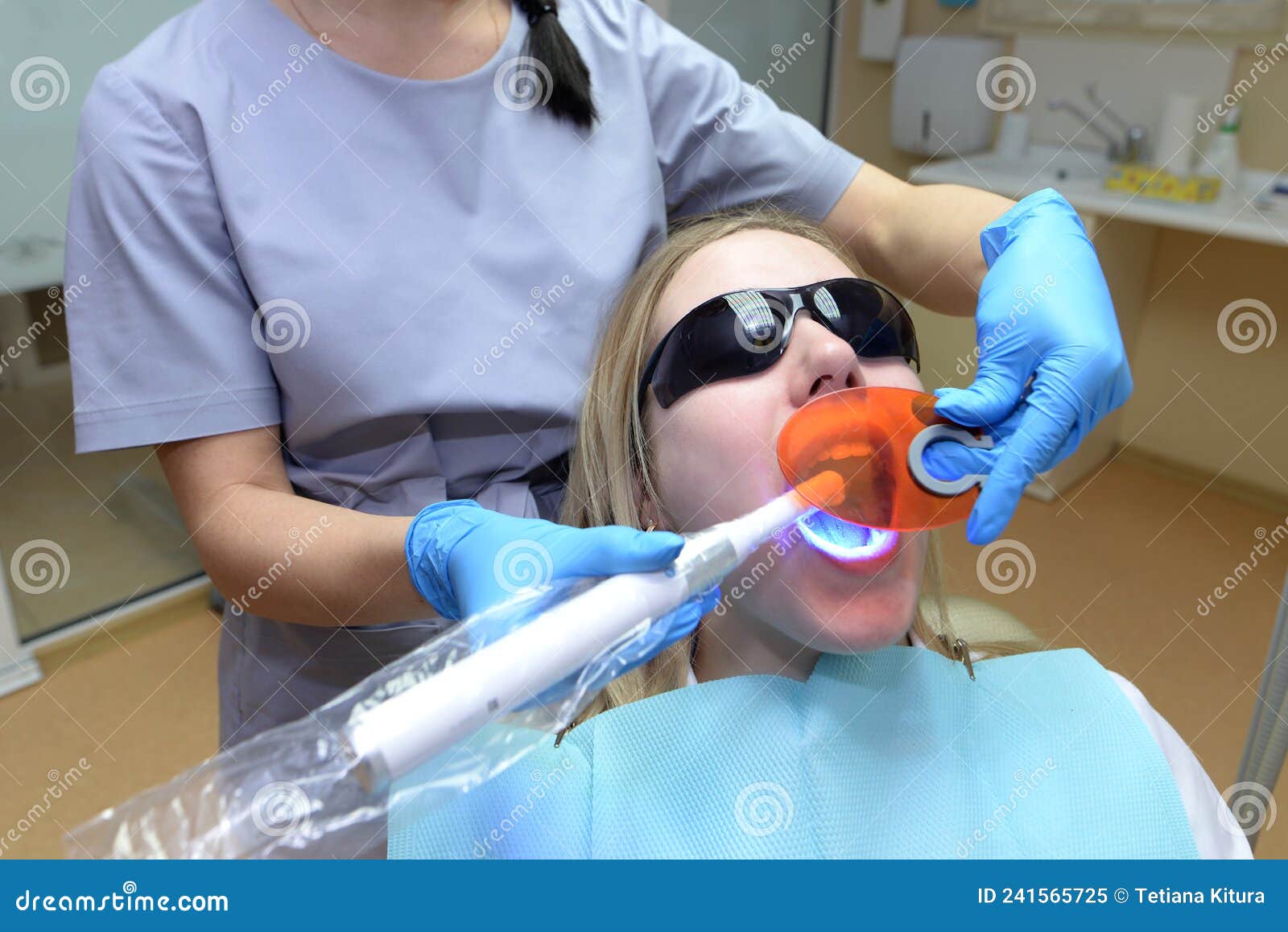 Girl Patient Wearing Protective Eyeglasses Lying On Chair In Dental Clinic Office Dentist