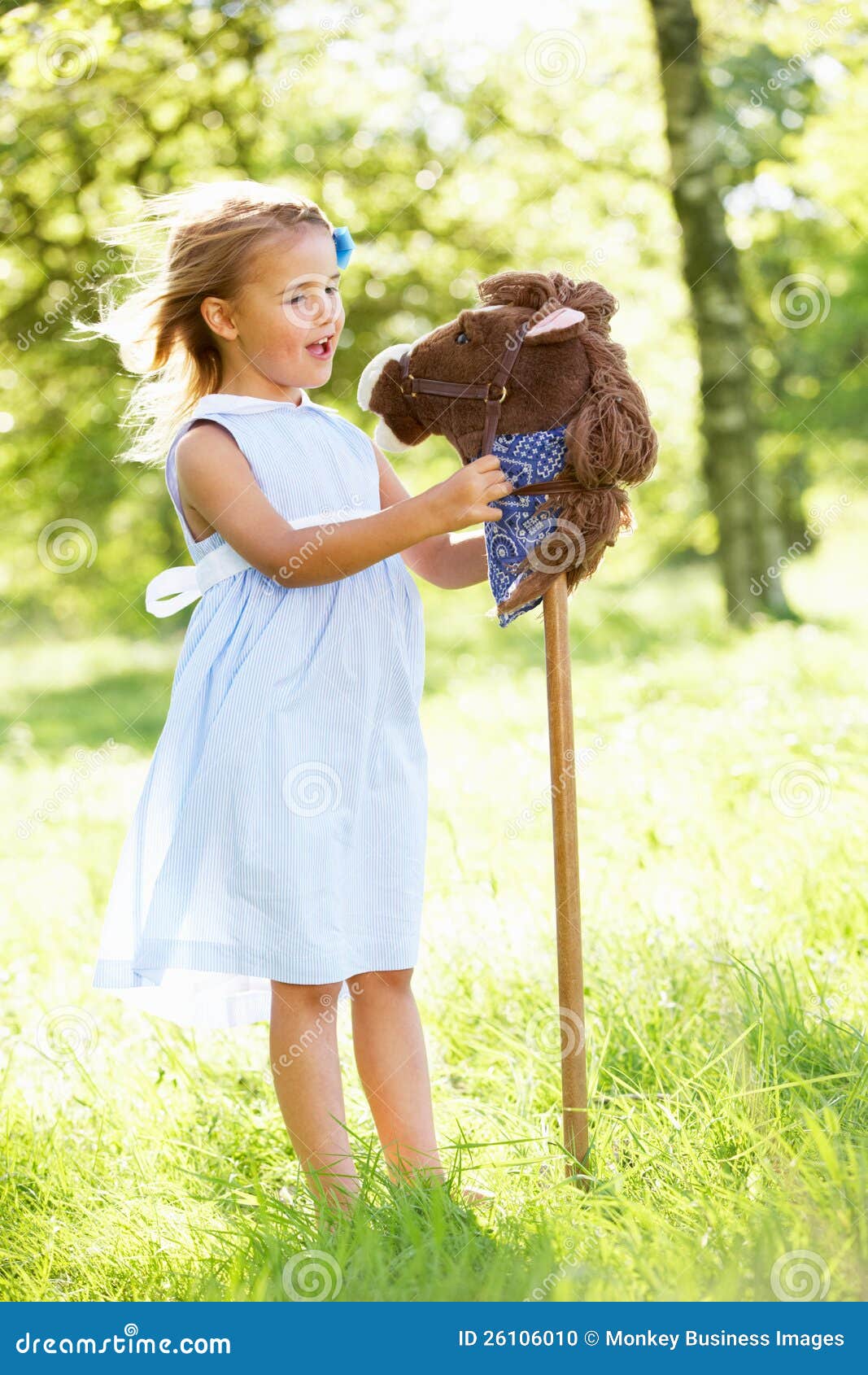 girl playing with hobby horse in summer field