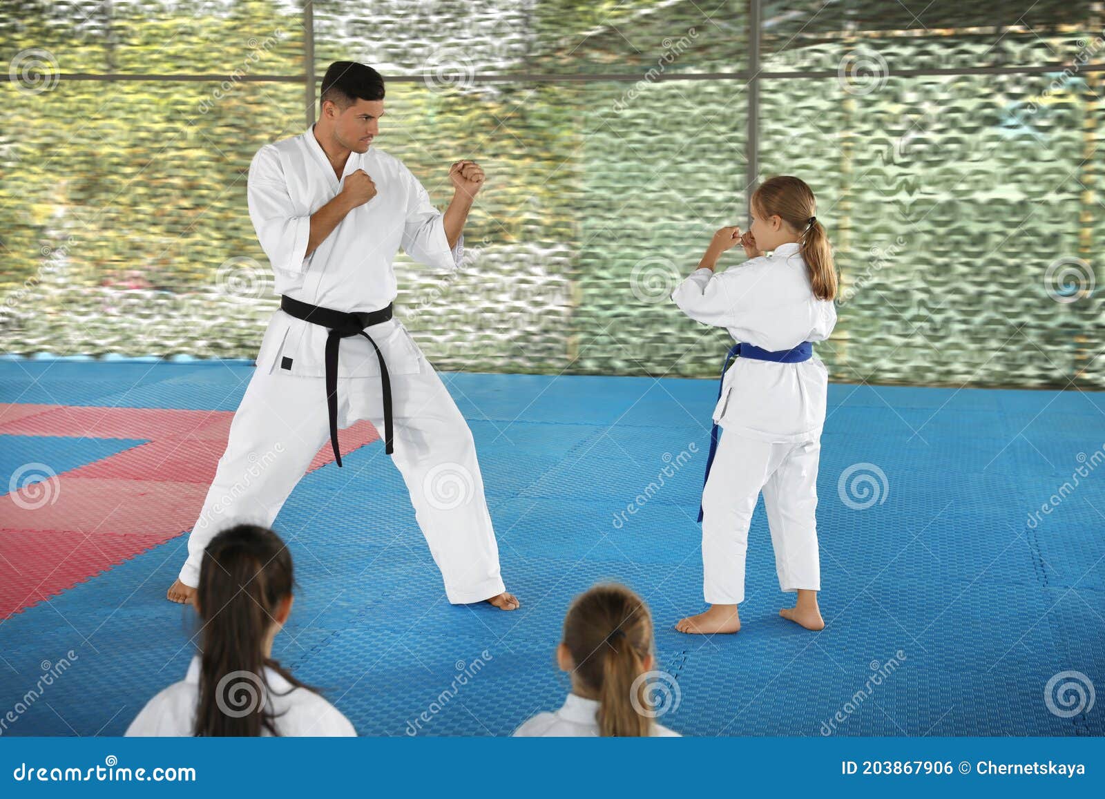 Girl Practicing Karate with Coach on Tatami Outdoors Stock Photo