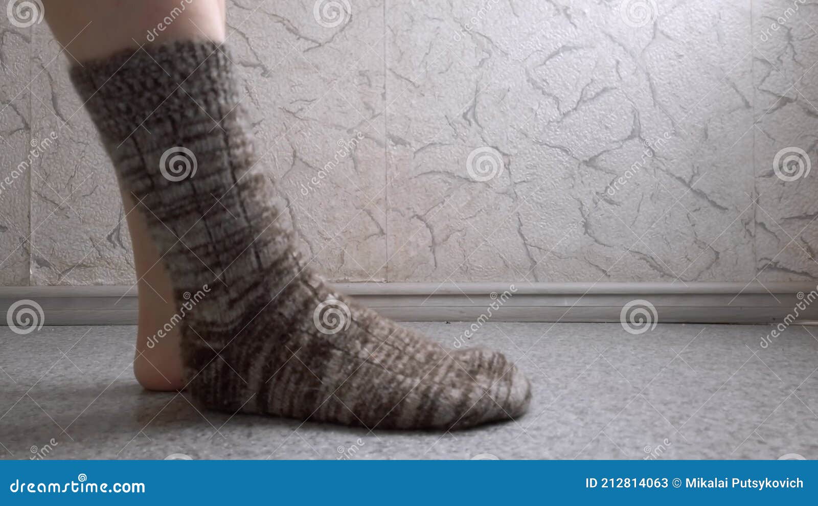 Closeup of female feet with a brown woolen sock on the left foot on the bed  Stock Photo by wirestock