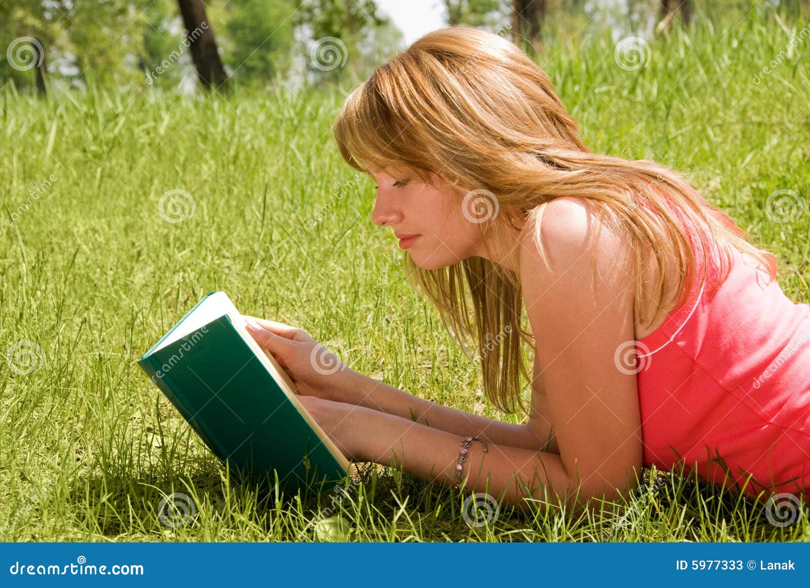 Attractive blond girl reading a book outdoor