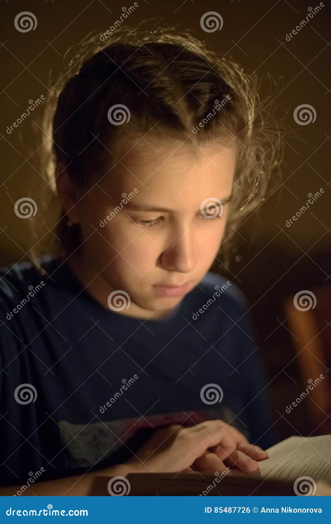 Girl`s Portrait with the Book in Reflected Candle Light Stock Photo
