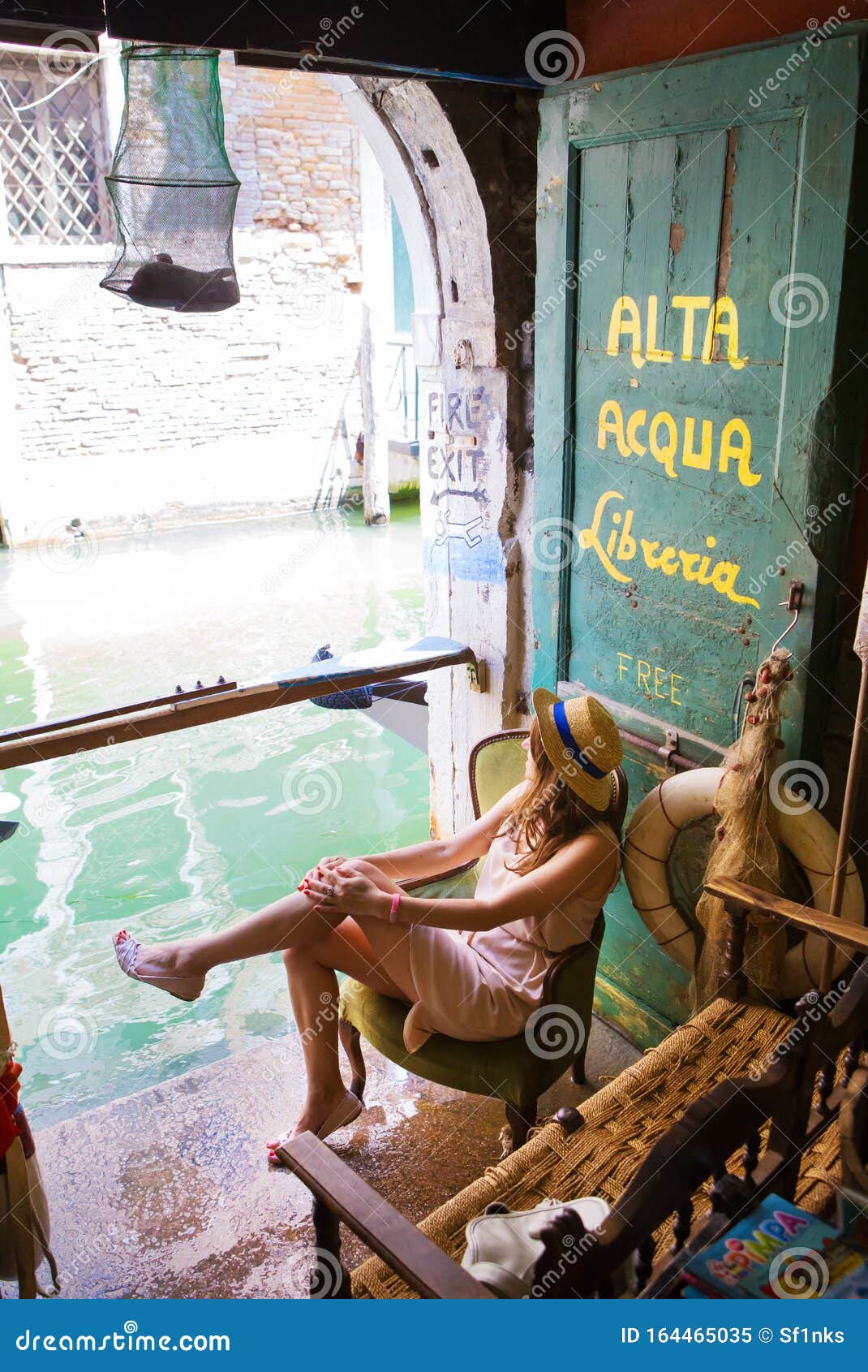 girl sits in a bookstore on the water of alta acqua libreria in venice, italy