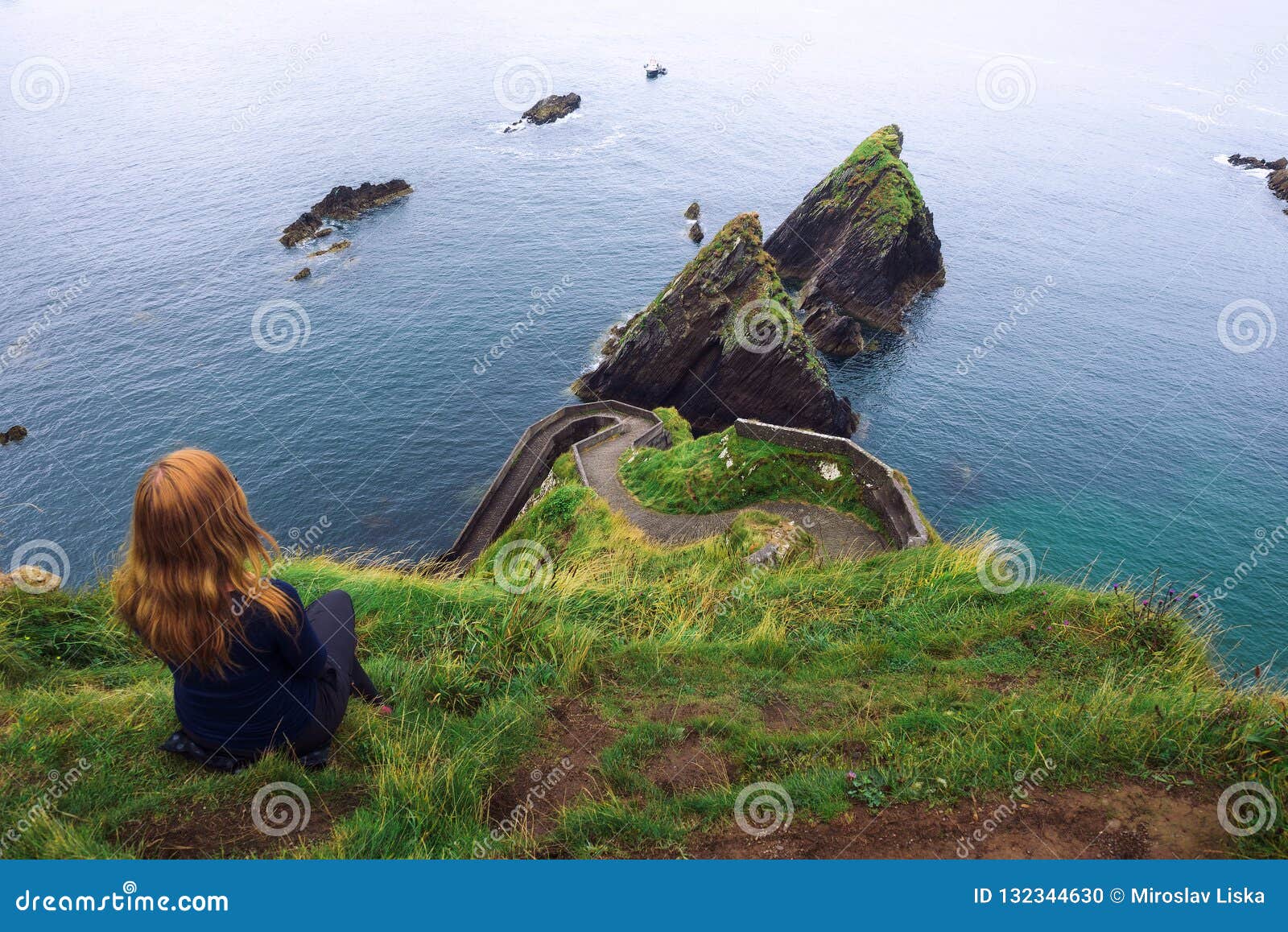 girl sits on a cliff over the ocean in ireland