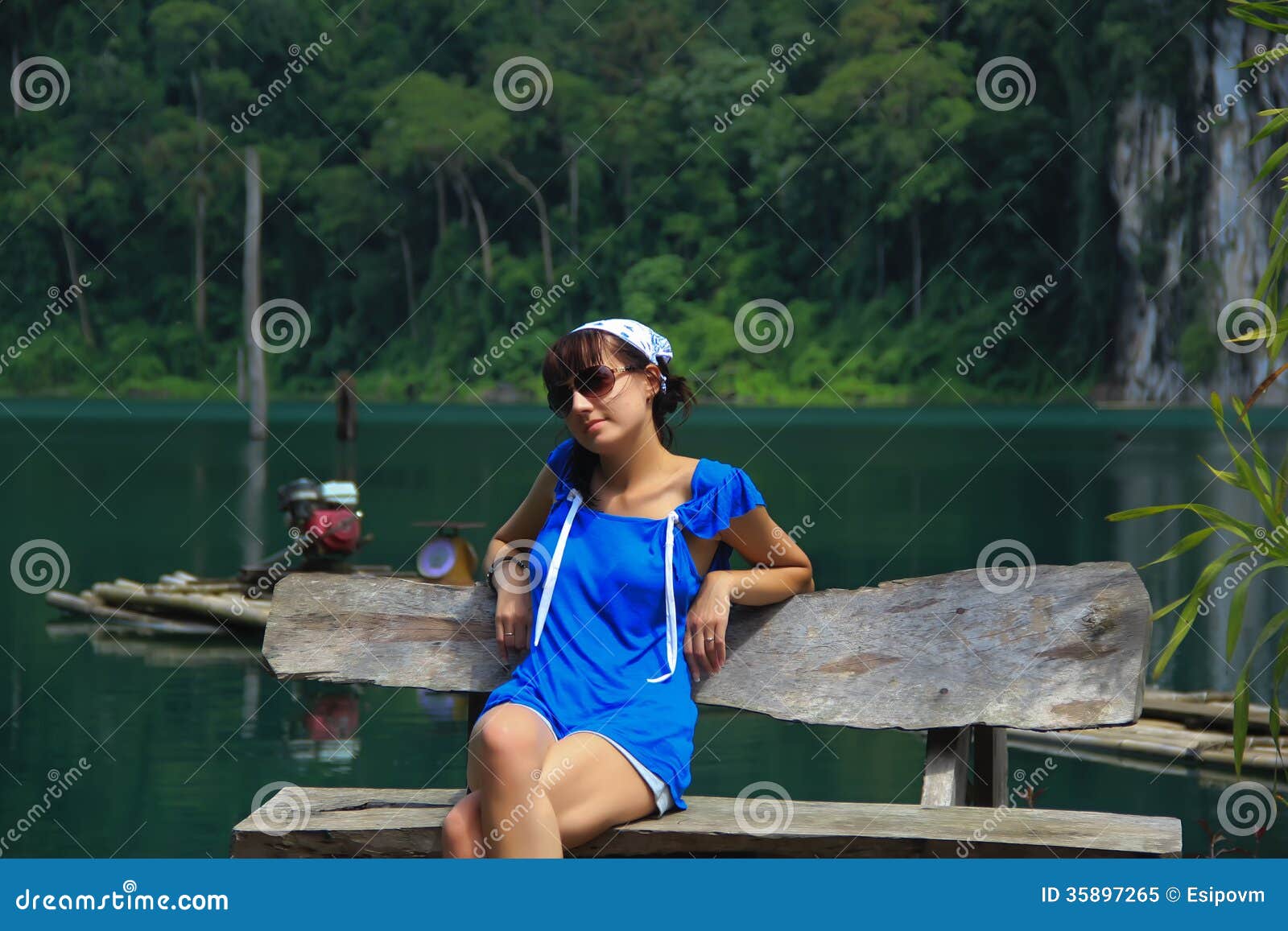Girl sits on the shores of lake. Girl in shorts sits on the shores of lake