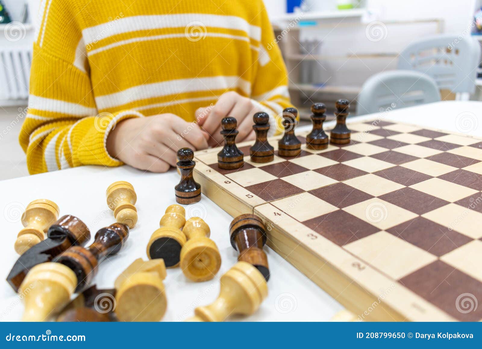 Girl in Striped Yellow Sweater is Playing Chess Game on Wooden Desk and ...
