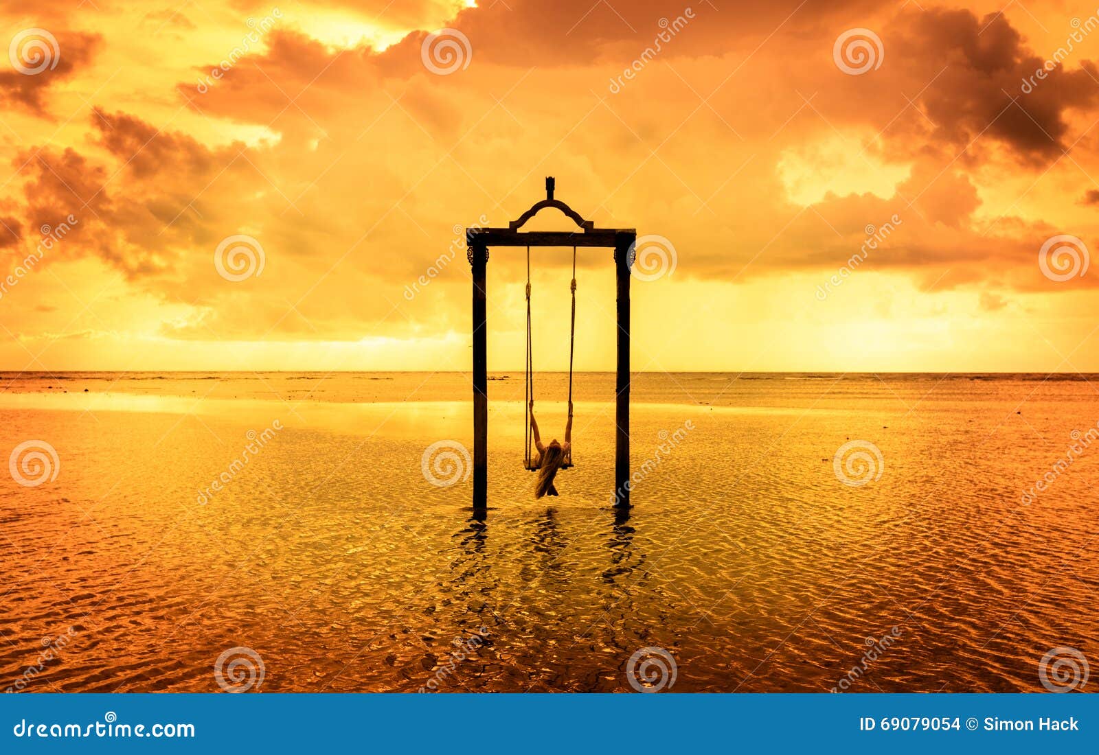 a girl on a swing over the sea at sunset in bali,indonesia 7
