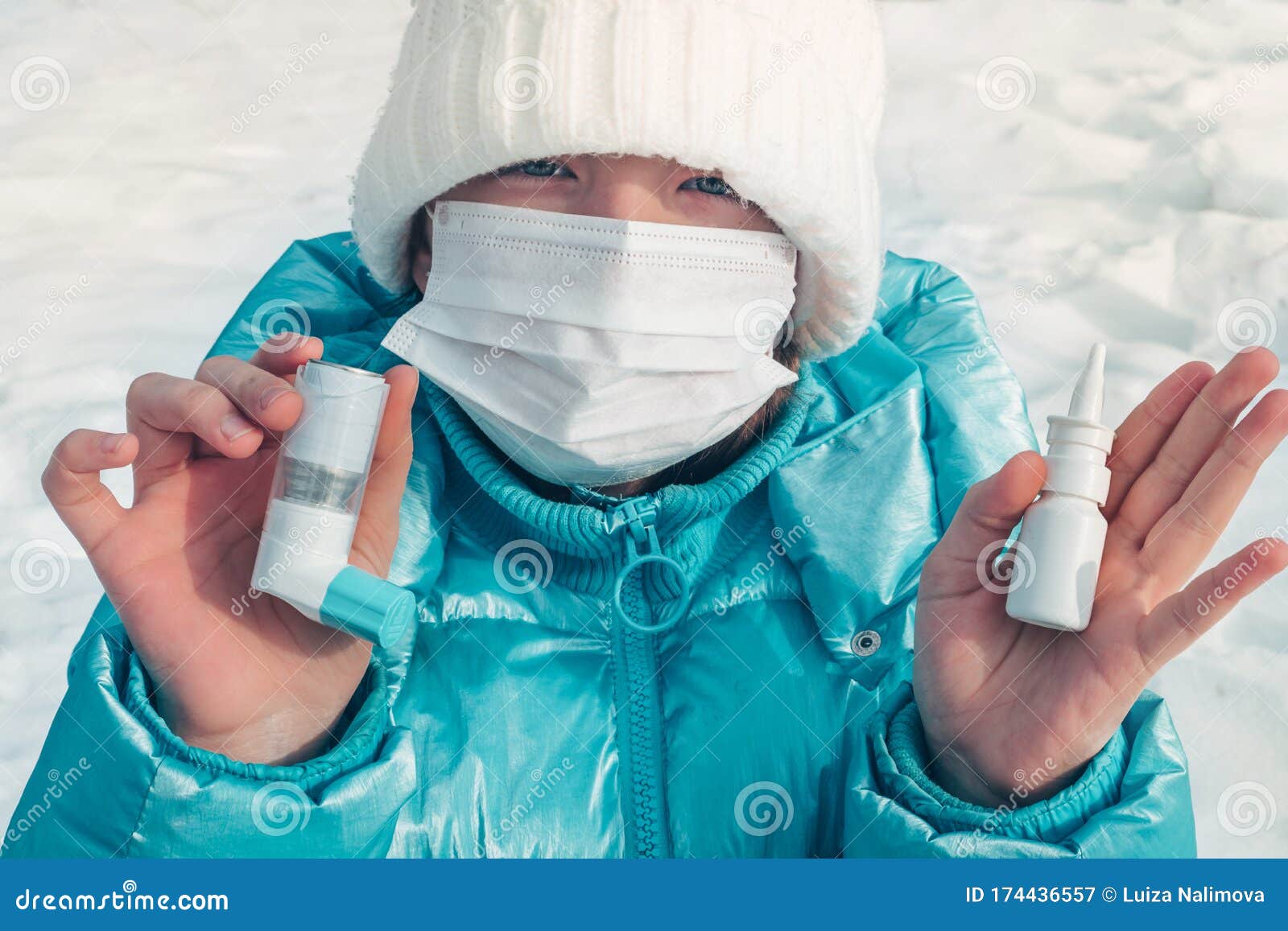 girl teenager holds in her hands drops for the nose and inhaler. walking in the winter park. face mask. flu season and cold