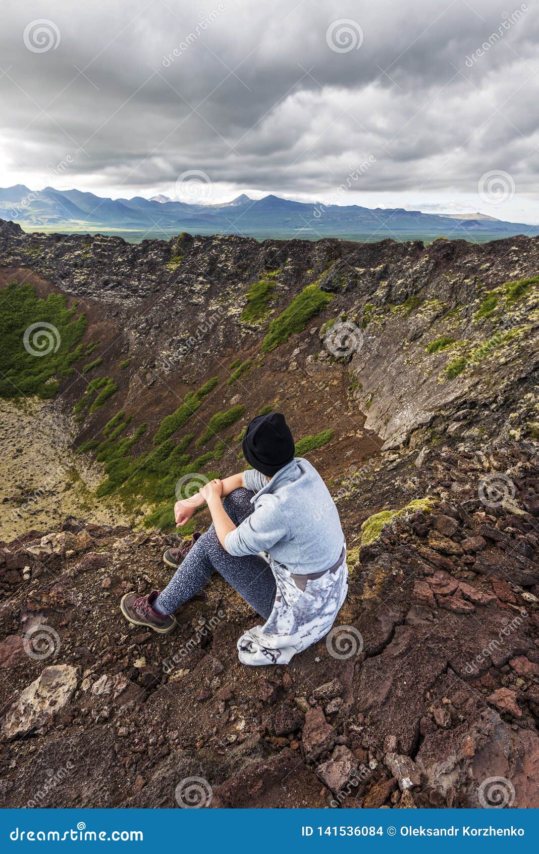 girl teenager is sitting in the border of eldborg volcano crater