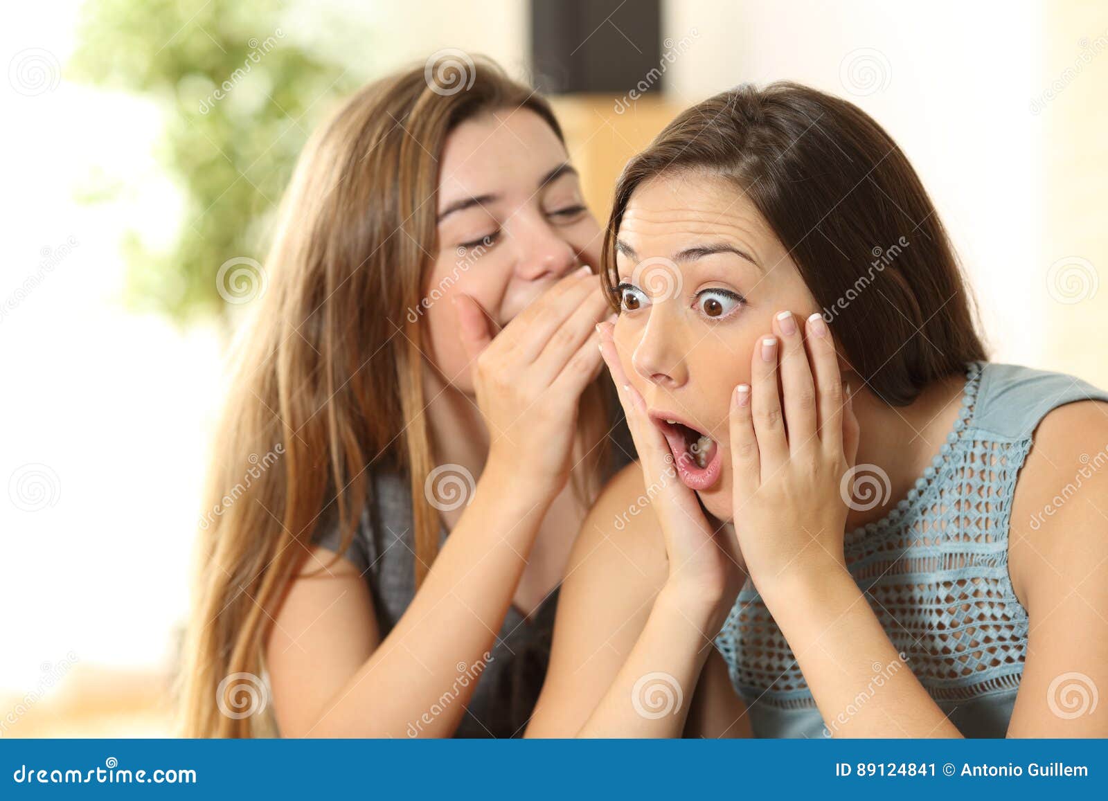 girl telling secrets to her amazed friend