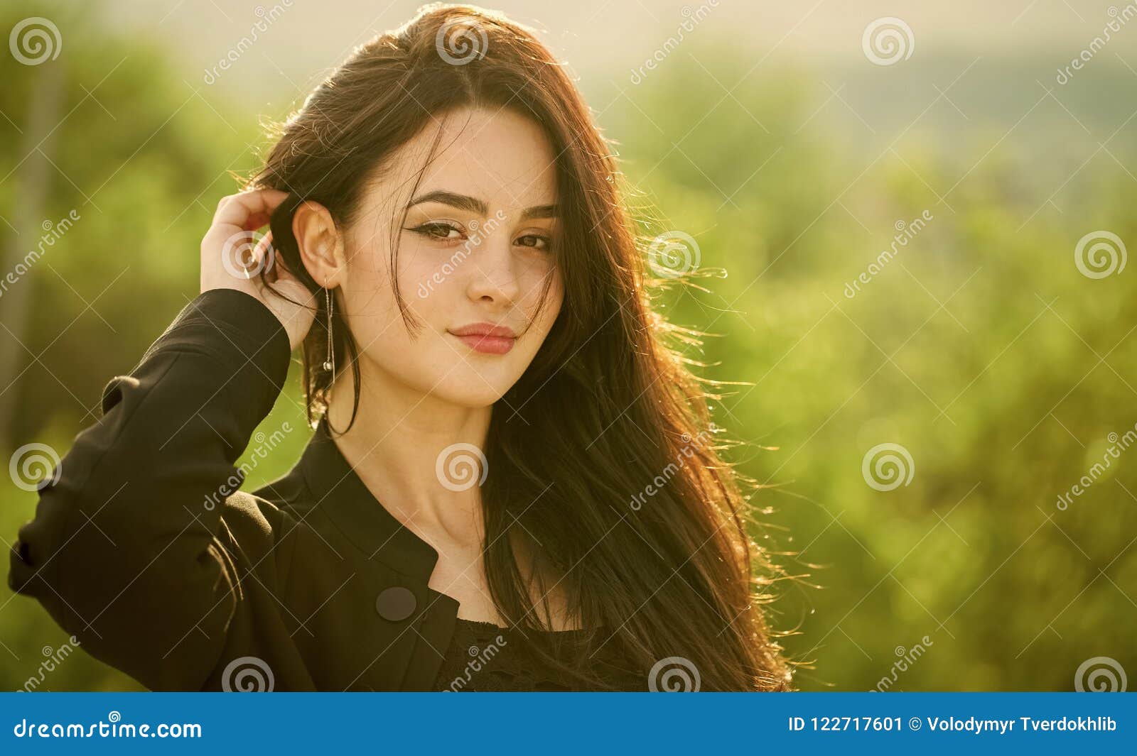 girl touch long brunette hair on natural landscape