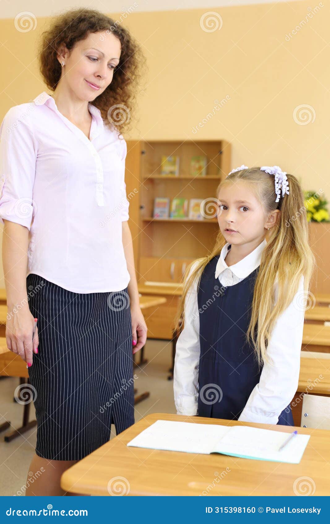 girl in uniform stands near school desk and