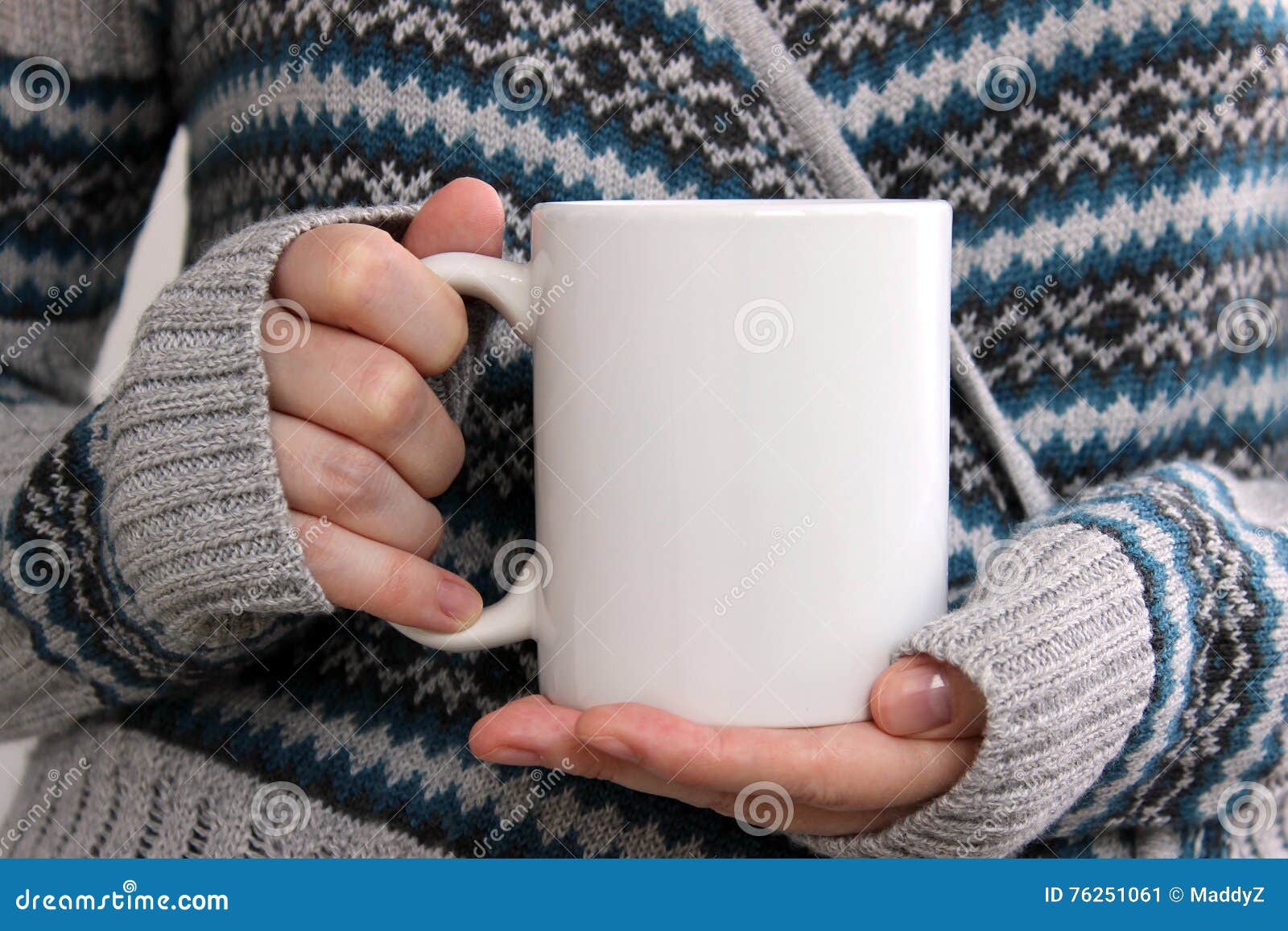 girl in a warm cardigan is holding white mug in hands.