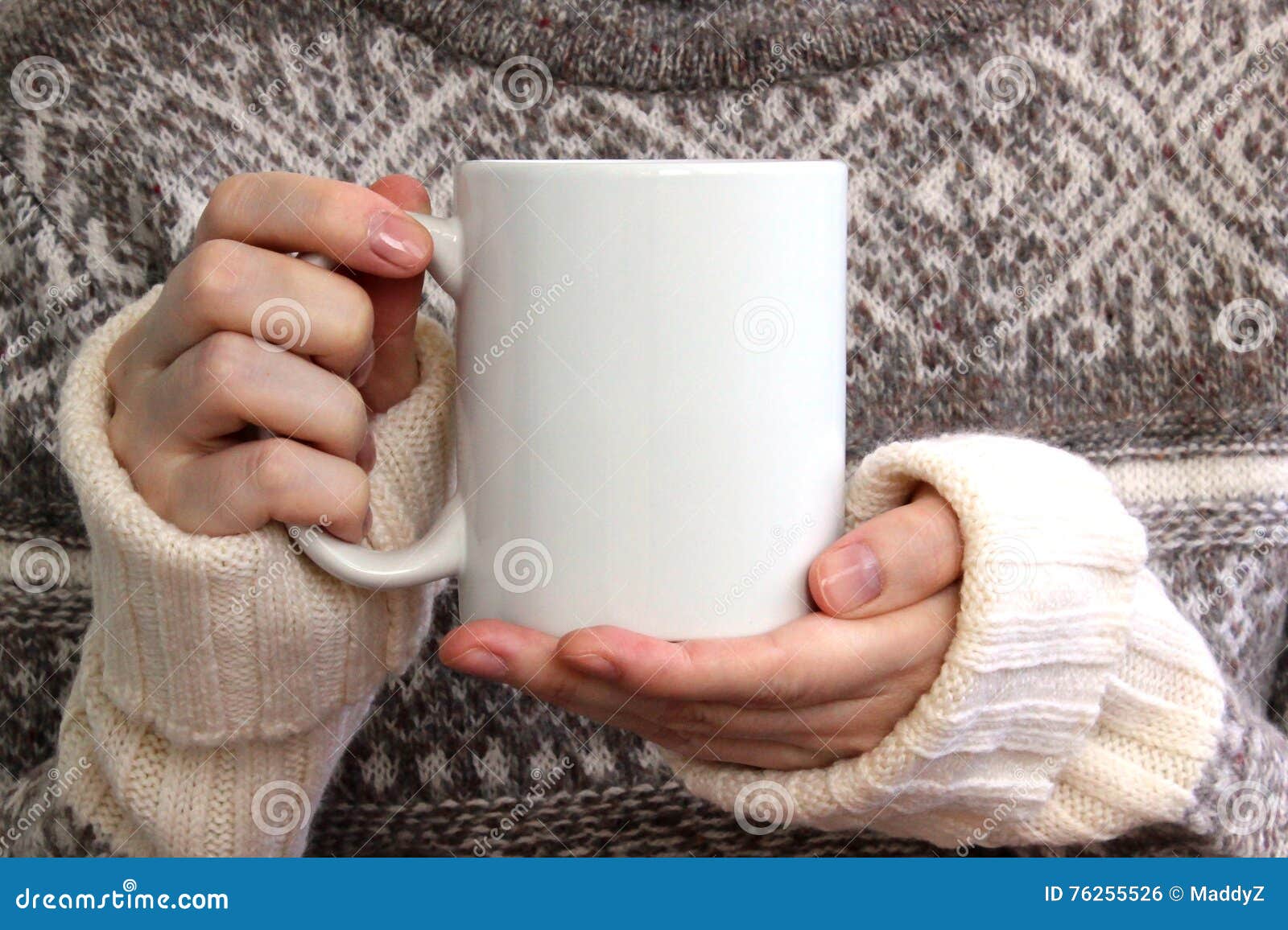 girl in a warm sweater is holding white mug in hands.