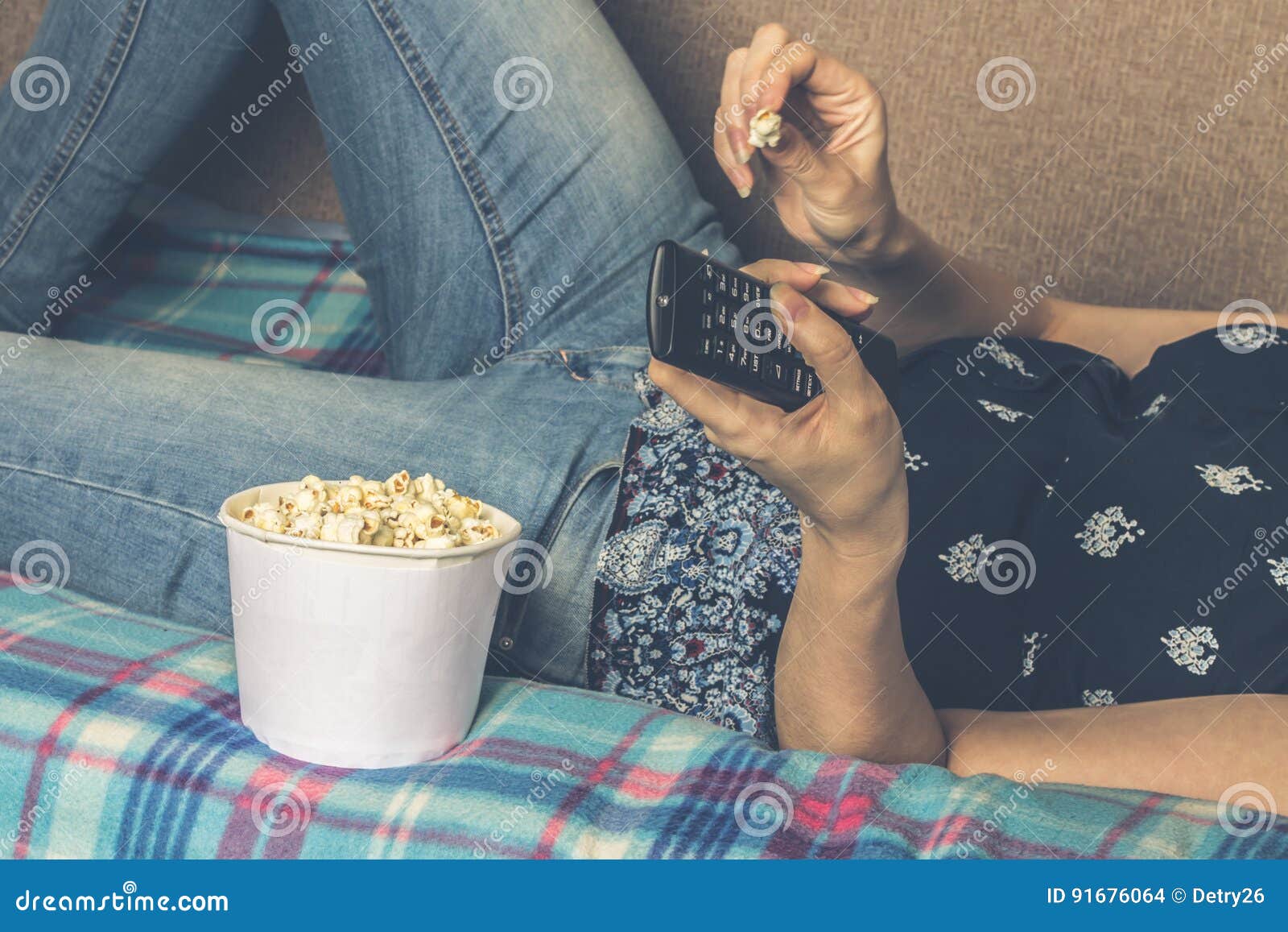 girl watching tv with popcorn at home in the living room. the concept of laziness