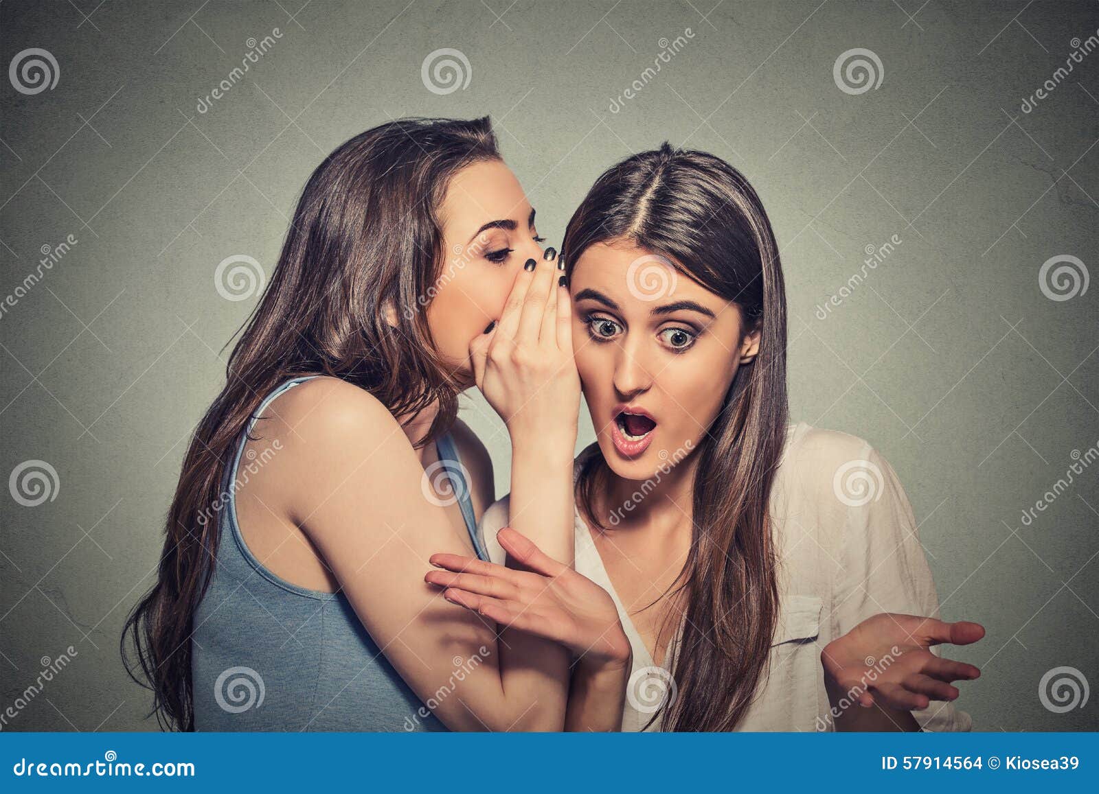 girl whispering into woman ear telling her shocking secret