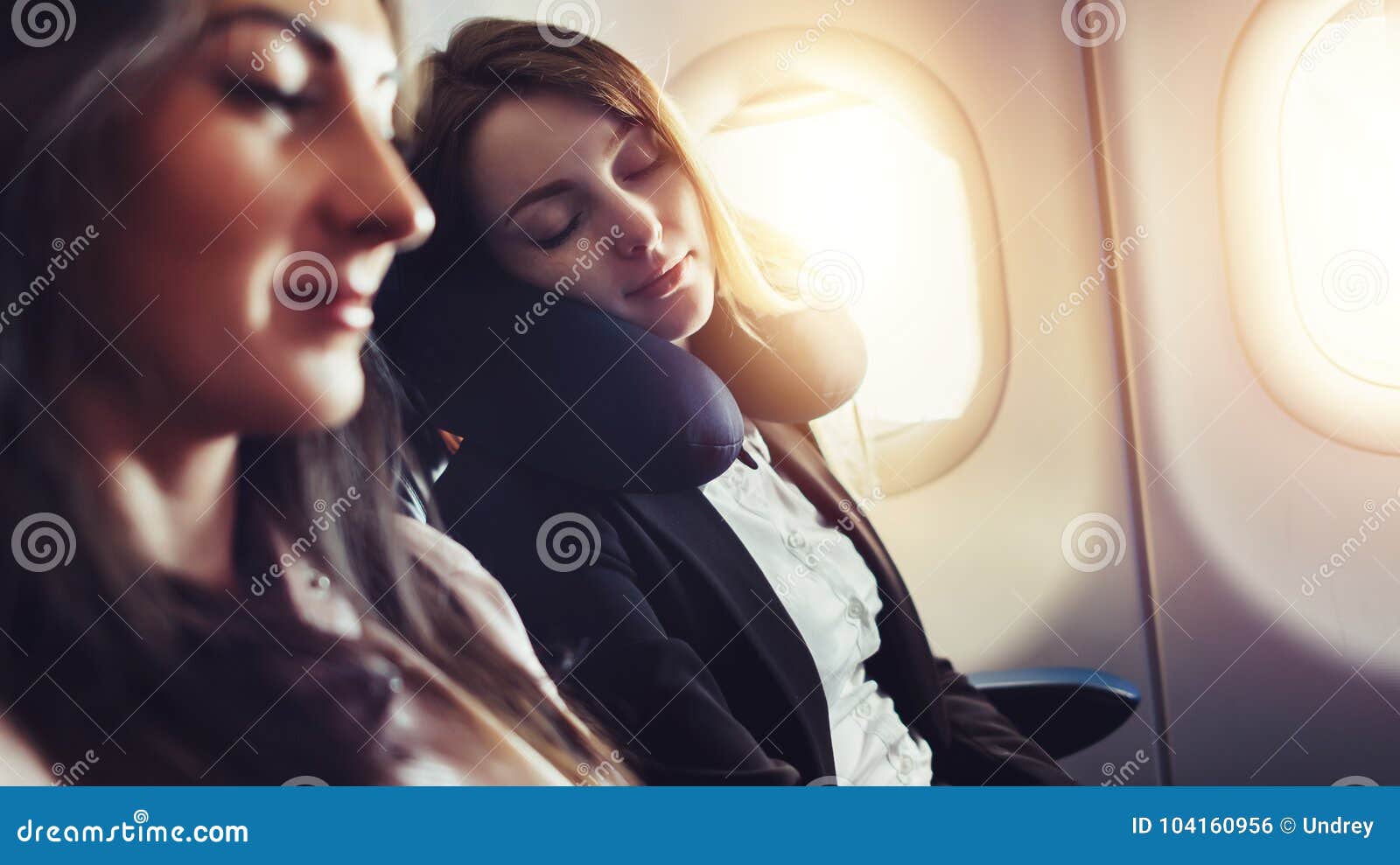 girlfriends traveling by plane. a female passenger sleeping on neck cushion in airplane.