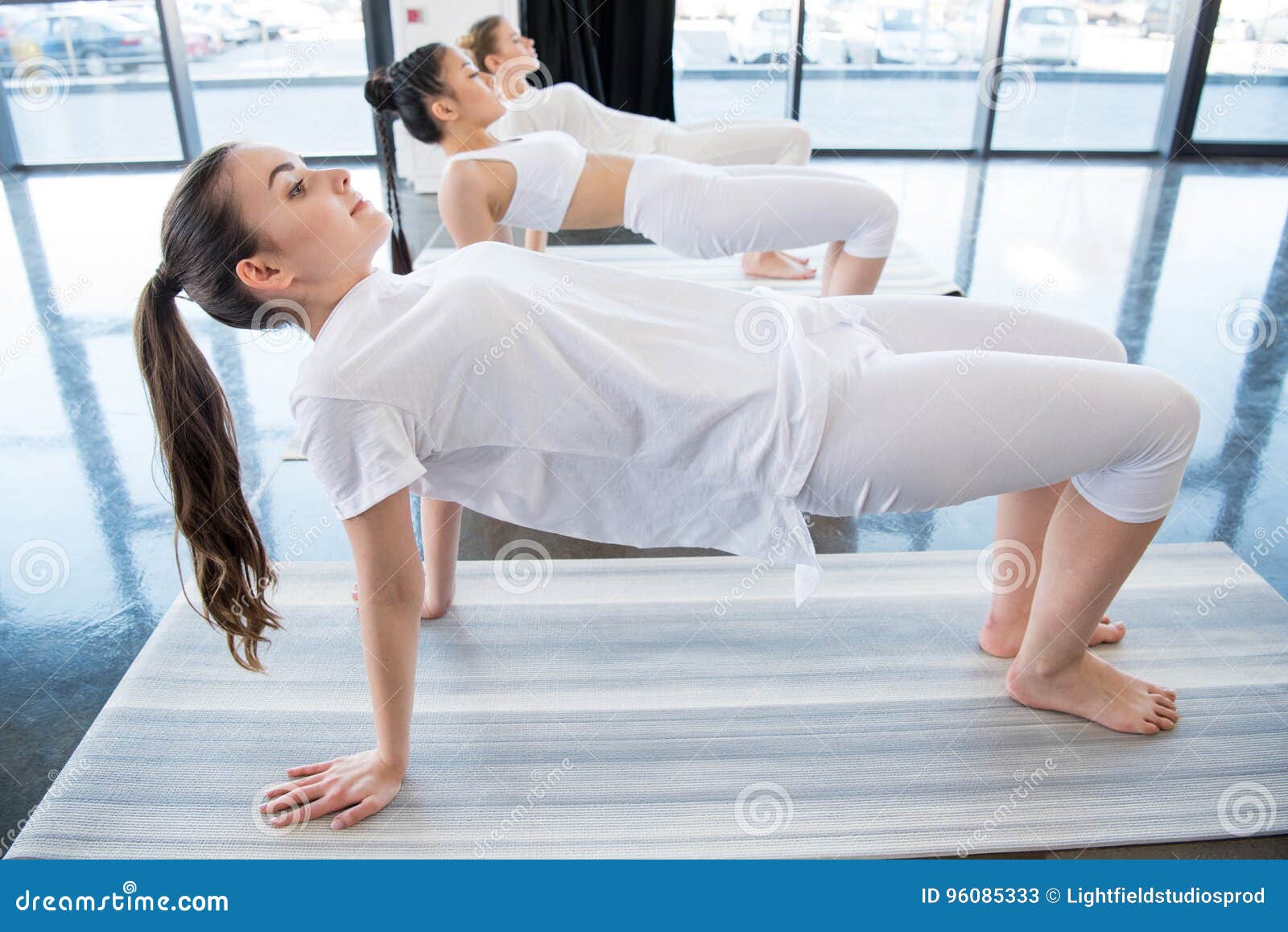 Girls in White Clothes Doing Half-wheel Pose Ardha Chakrasana Indoors ...