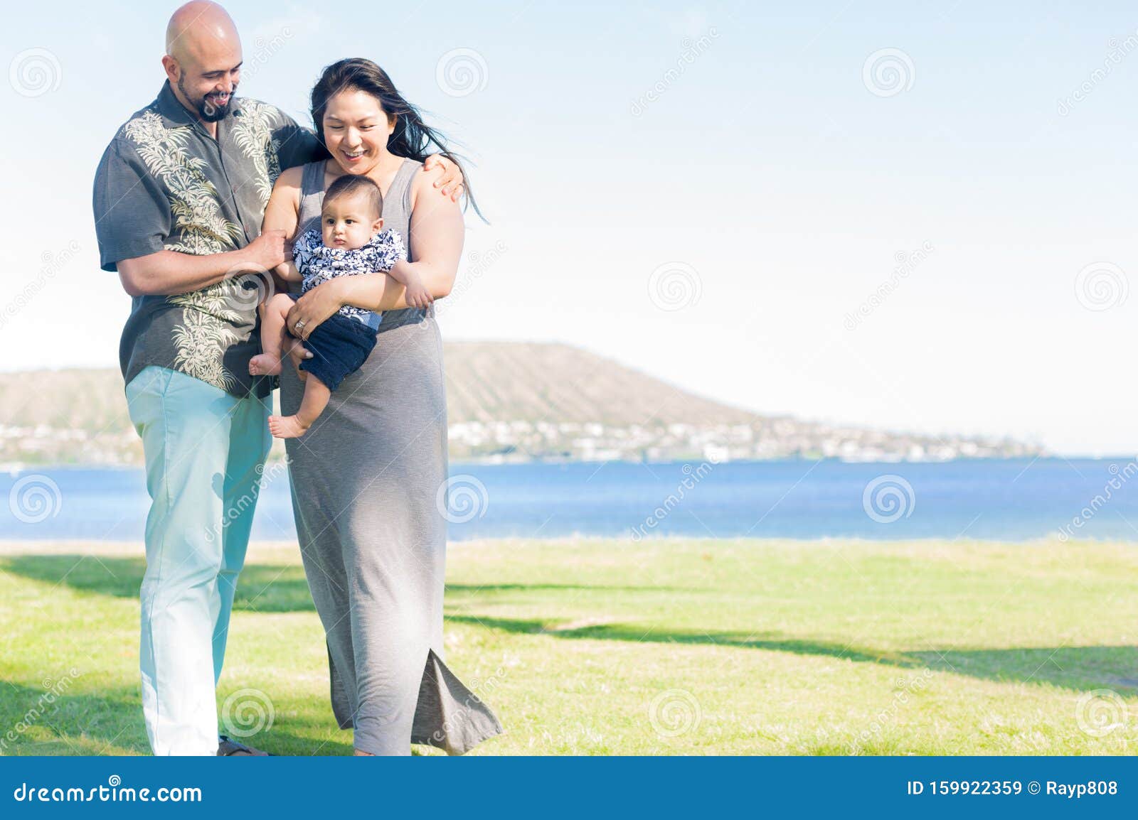 Glad familjeporträtt på stranden. Fader och mor som håller sitt barn på stranden utomhus tillsammans, porträtt