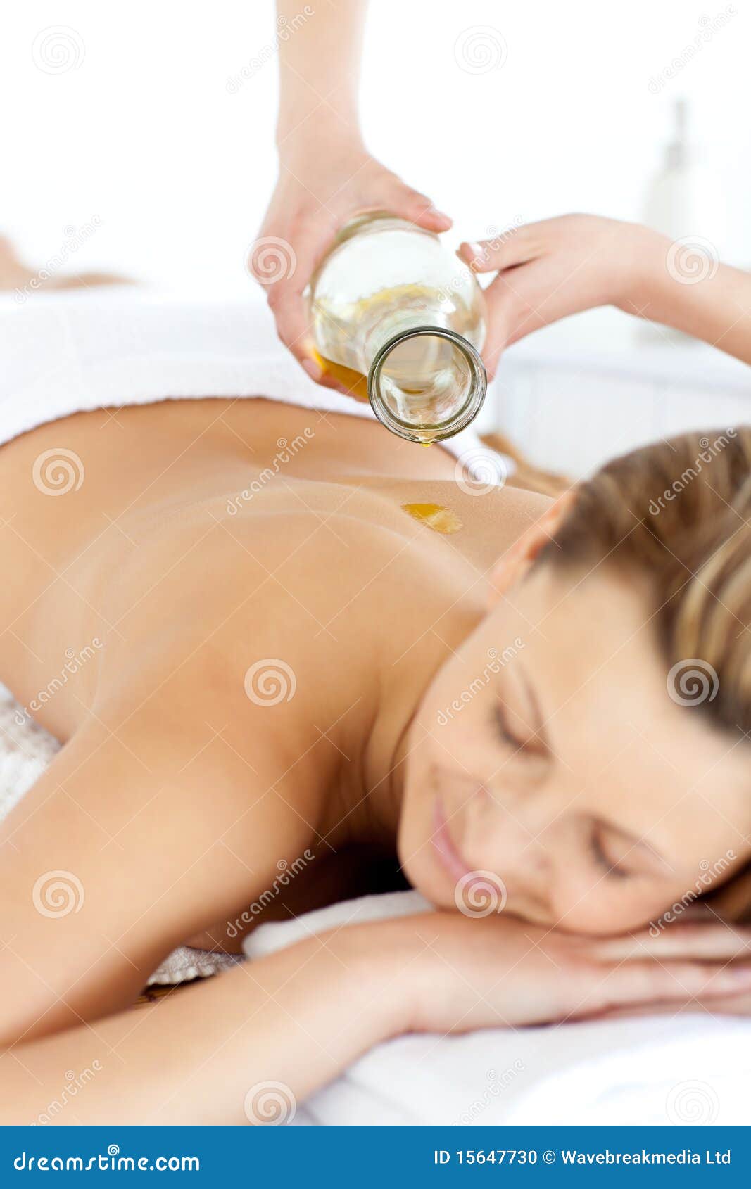 glad young woman enjoying a back massage with oil