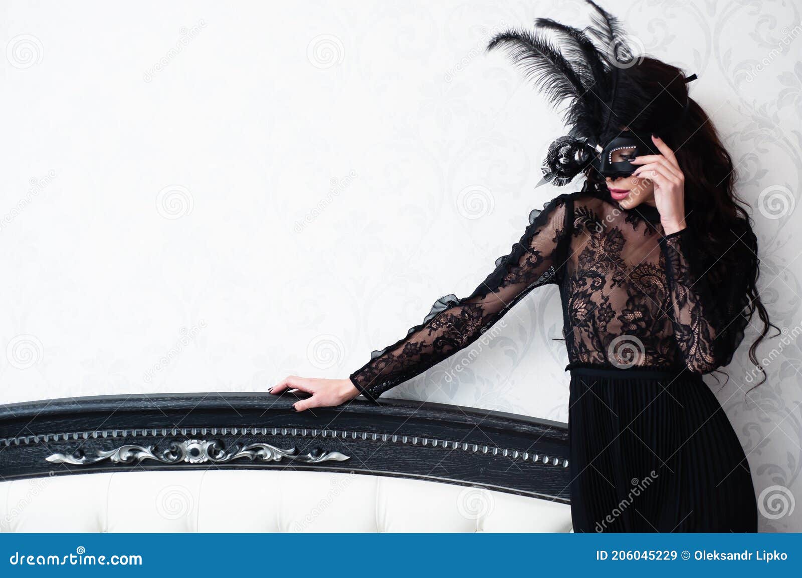 glamorous brunette lady with a beautiful hairstyle and red lips, in an evening dress, a venetian black mask with stylish accessori