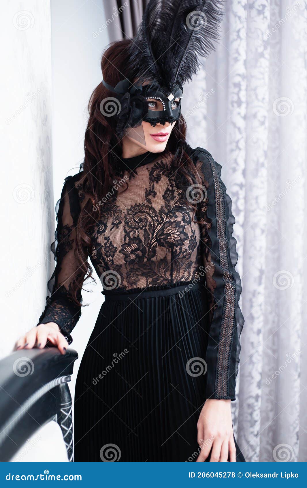 glamorous brunette lady with a beautiful hairstyle and red lips, in an evening dress, a venetian black mask with stylish accessori