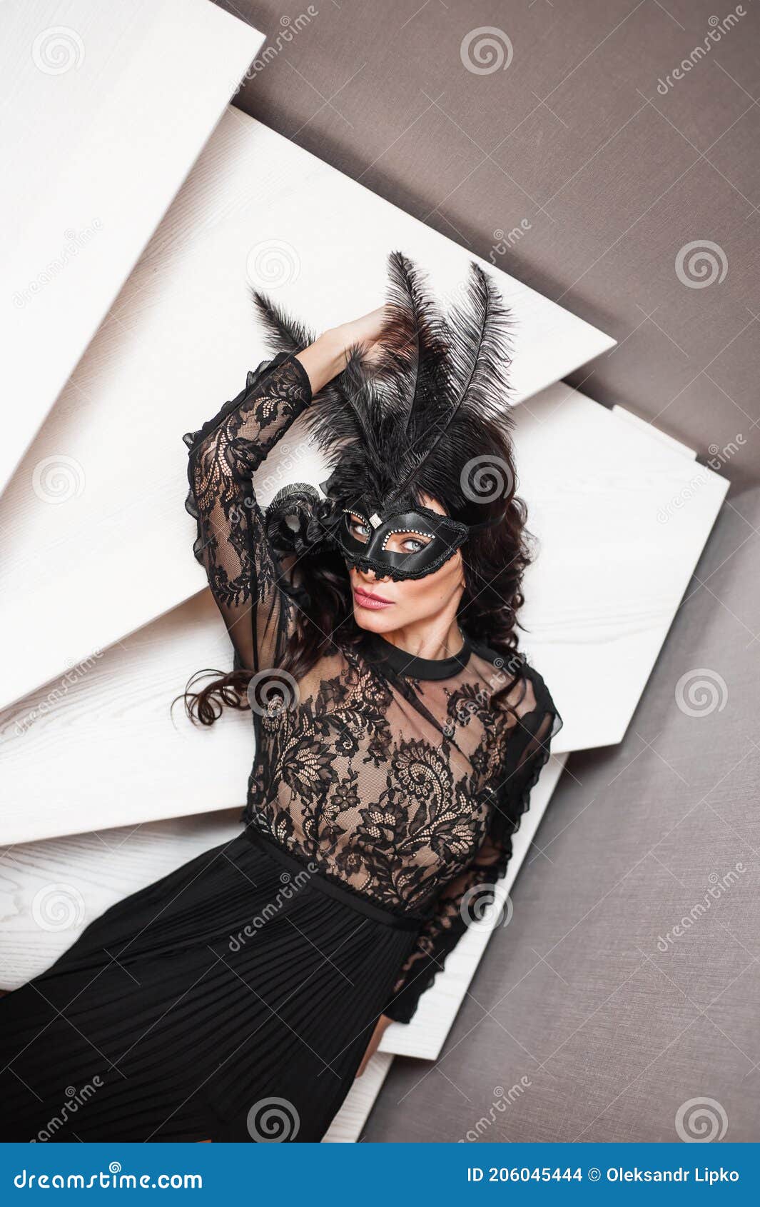 glamorous brunette lady with a beautiful hairstyle and red lips, in an evening dress, a venetian black mask with stylish accessori