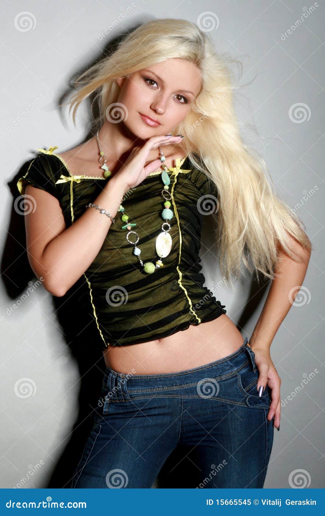 Young woman in stylish tight jeans, wearing crop top with handbag walking  outdoors in summer season, rear view. Woman wearing blue skinny jeans and crop  top shirts walking on city street. Stock