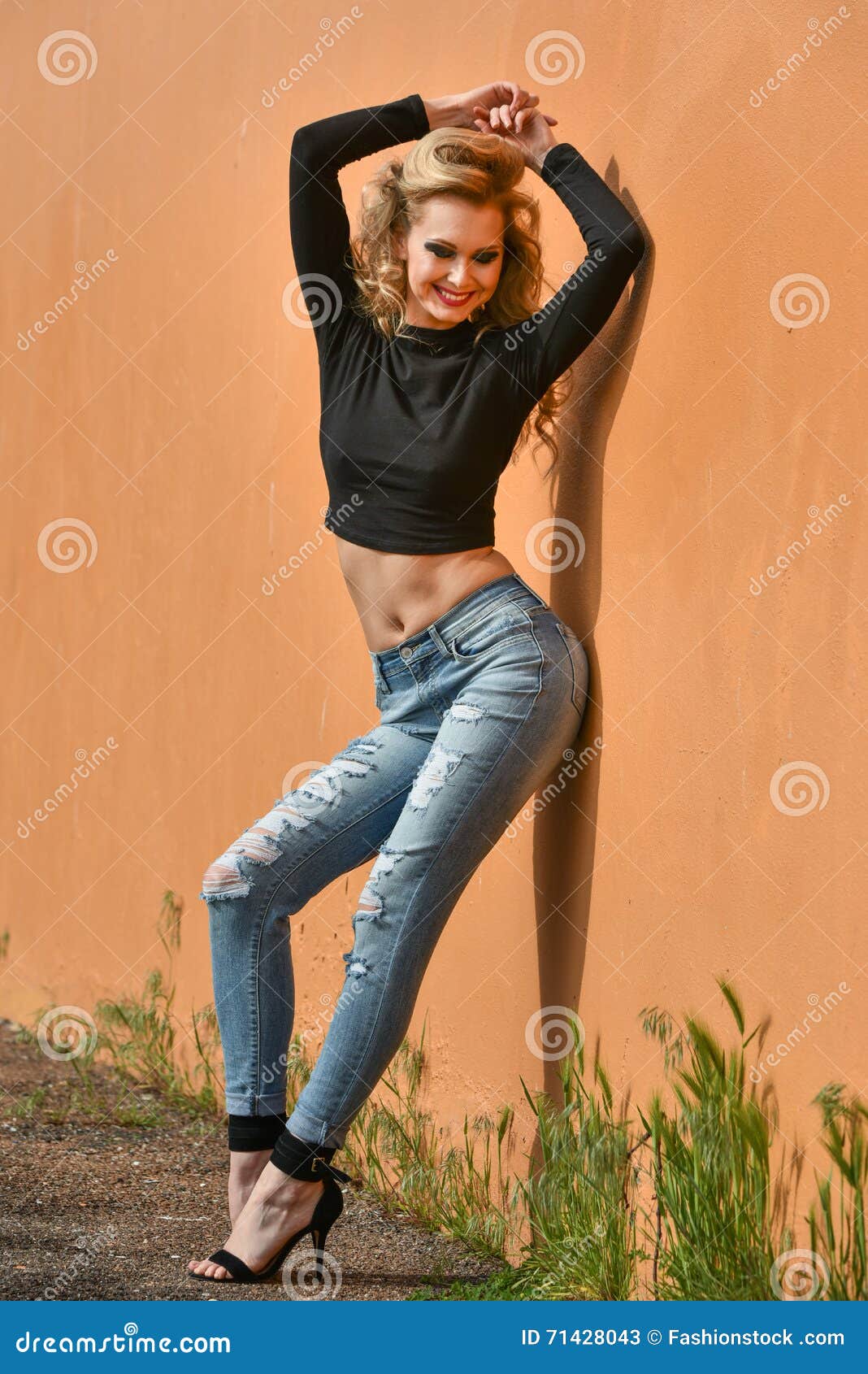 Portrait. Fashionable girl blogger with braids posing outdoors in jeans and  a black trendy T-shirt and black sneakers on a sunny summer day. Stock  Photo | Adobe Stock