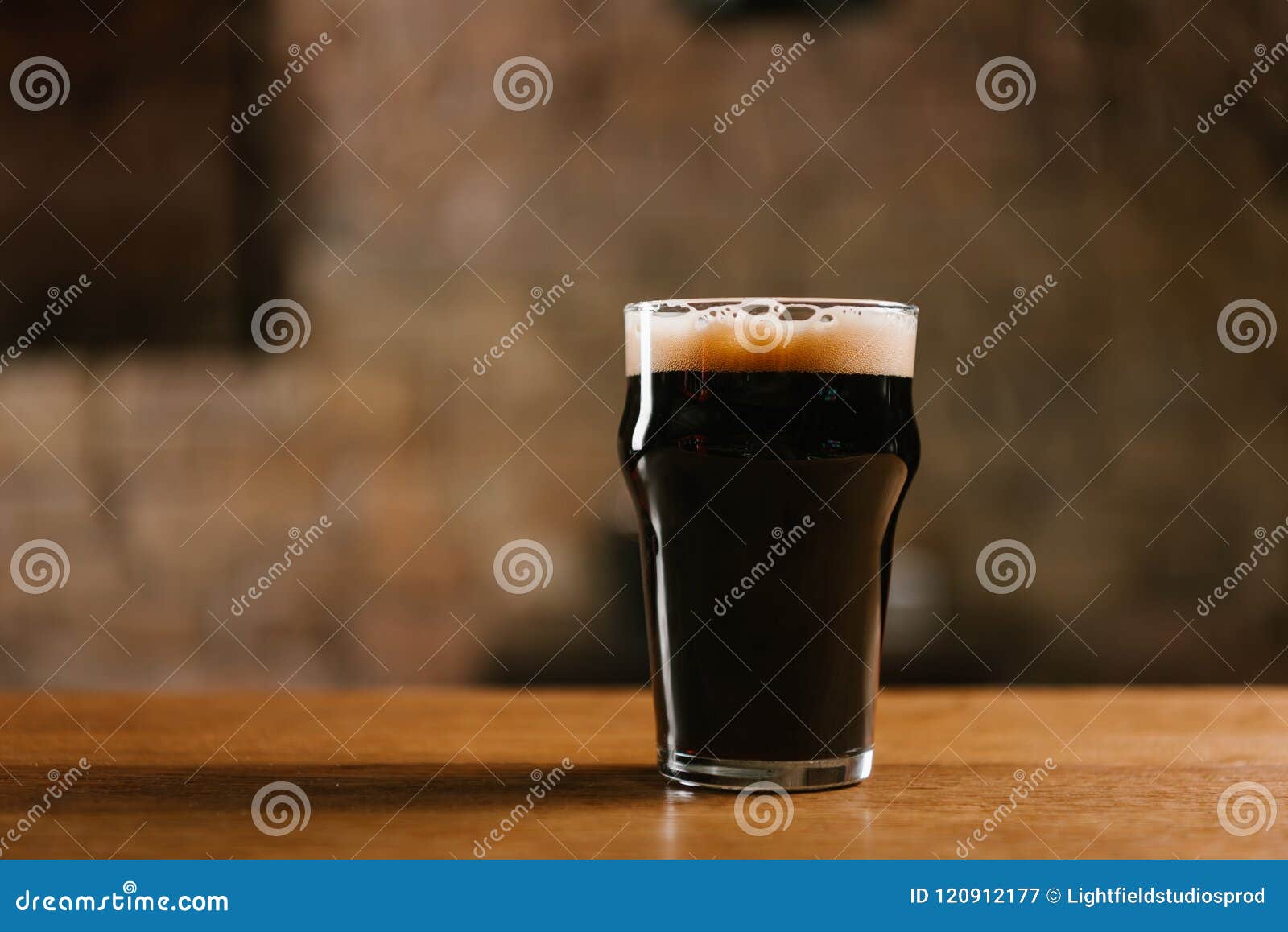 Glas frisches kaltes dunkles Bier auf Holztisch in der Kneipe