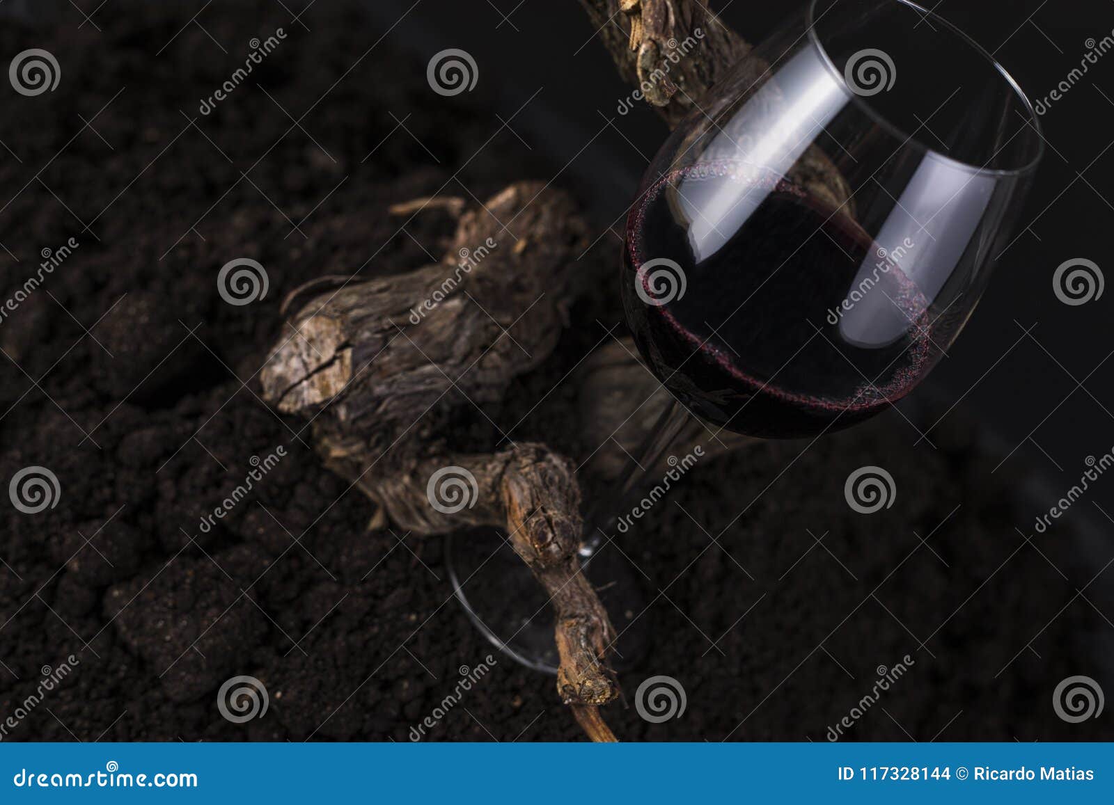 Glas Rotwein mit Rebe in einem schwarzen Hintergrund. Glas Rotwein mit traditioneller hölzerner Rebe in einem schwarzen Hintergrund