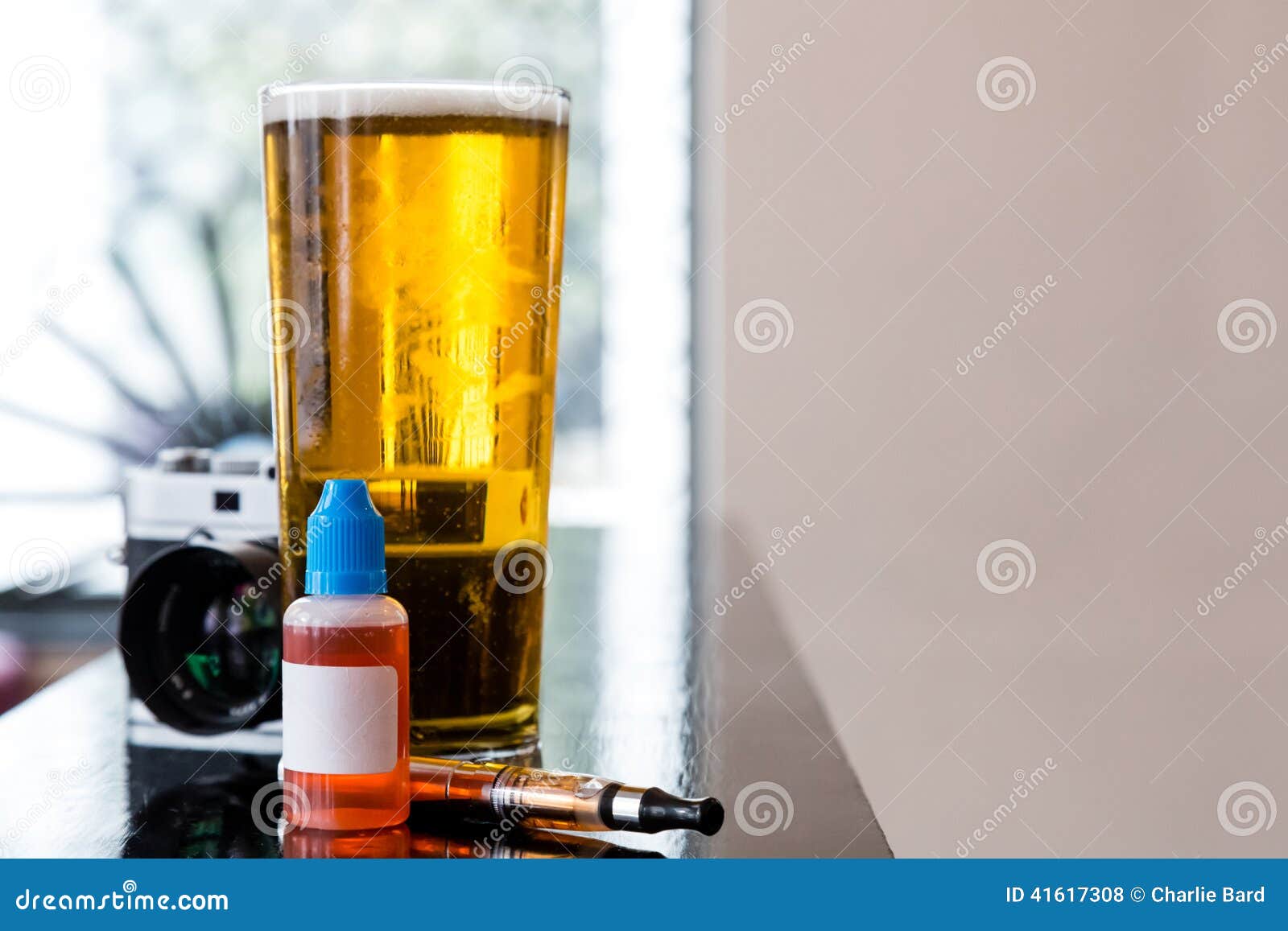 Glass of beer and gadgets on table. Tall glass of beer and miscellaneous gadgets on table