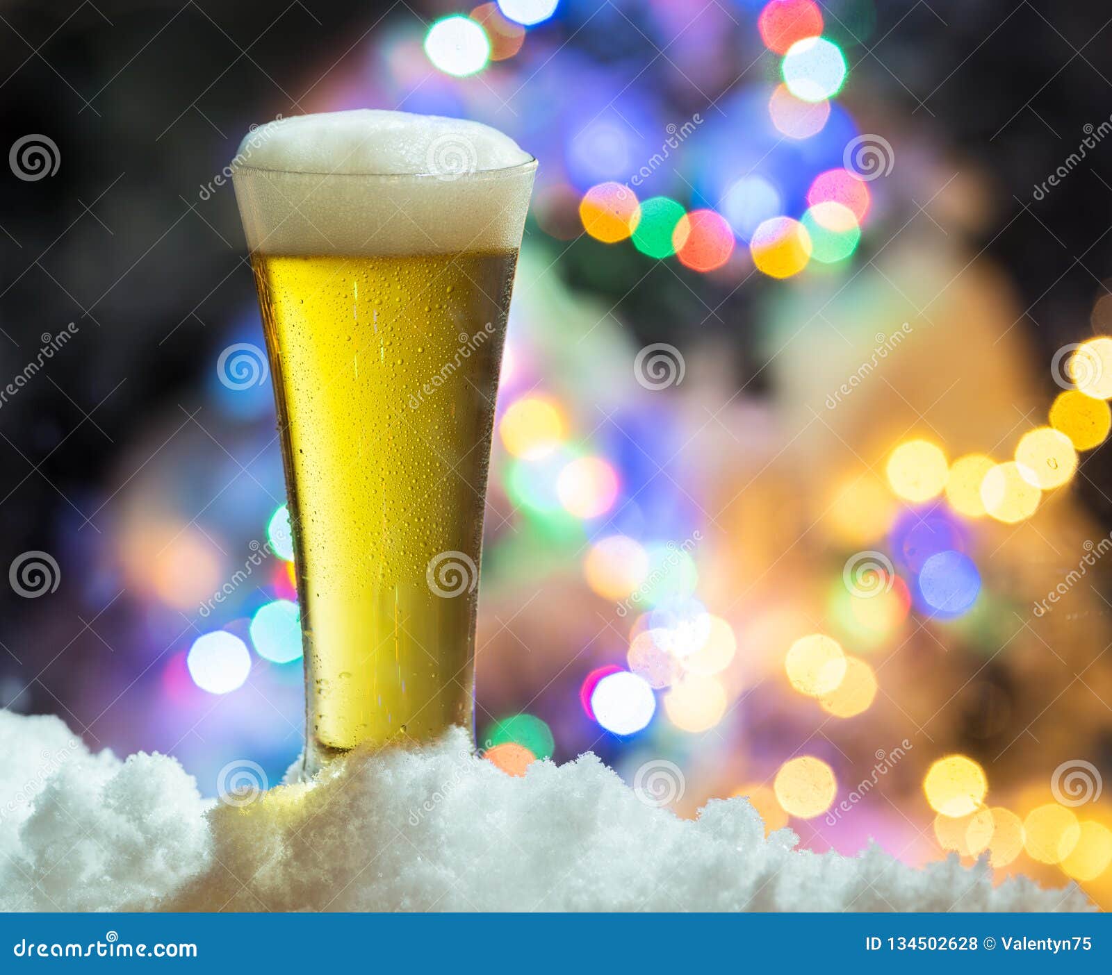 Glass of Beer with Magic Christmas Lights at the Background Stock Photo