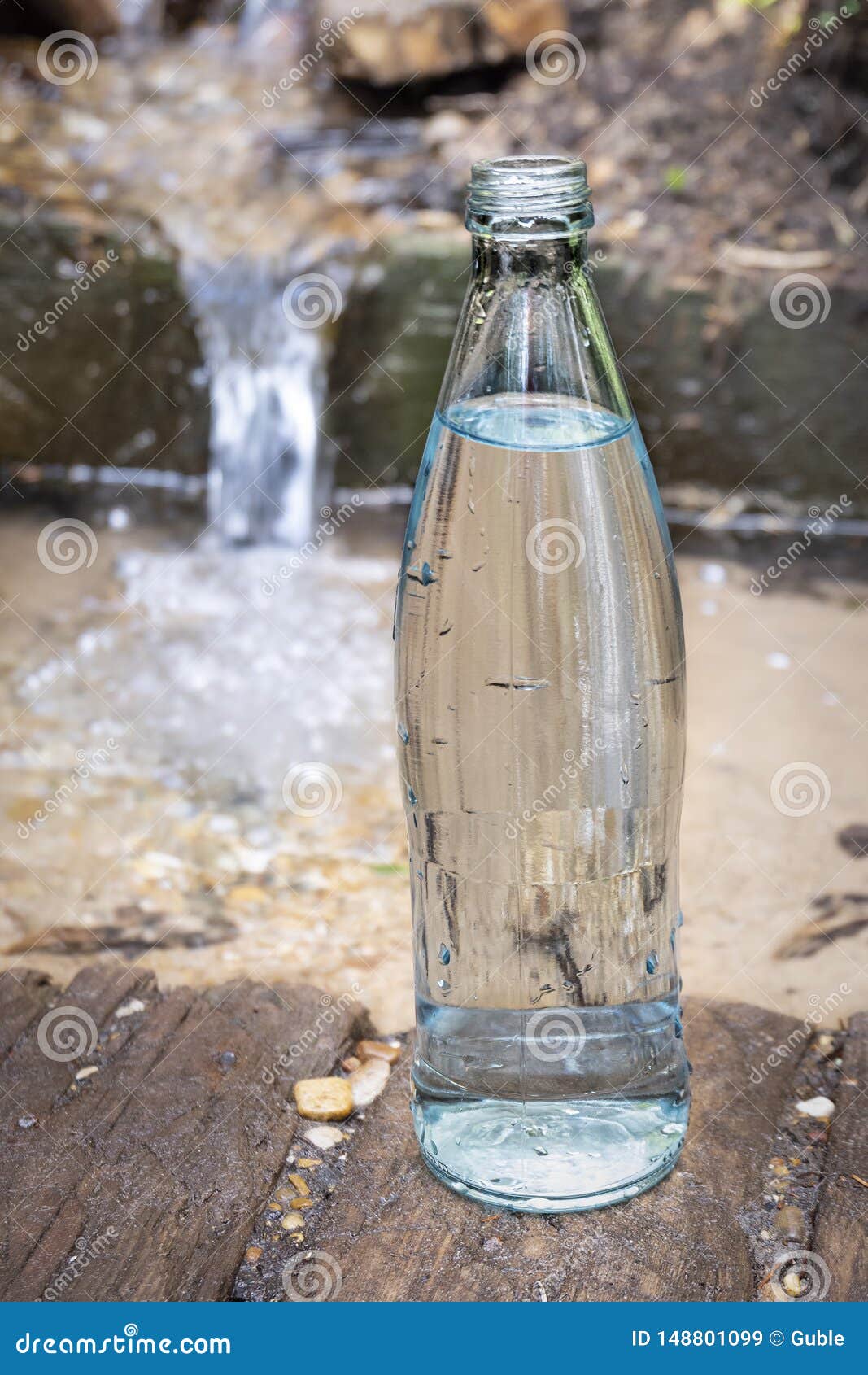 Glass Bottle On The Background Of Pure Spring Water. Clean Natural
