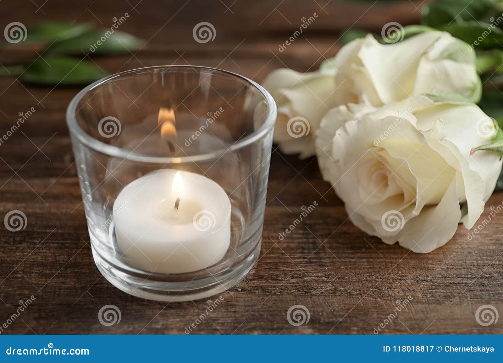 Glass Holder With Burning Wax Candle Near Roses On Wooden
