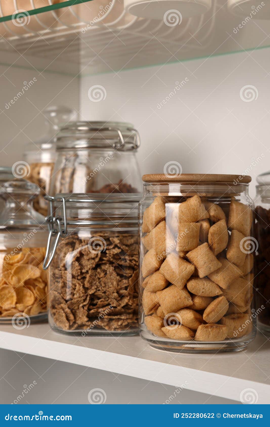Glass Containers with Different Breakfast Cereals on Shelf Stock Photo